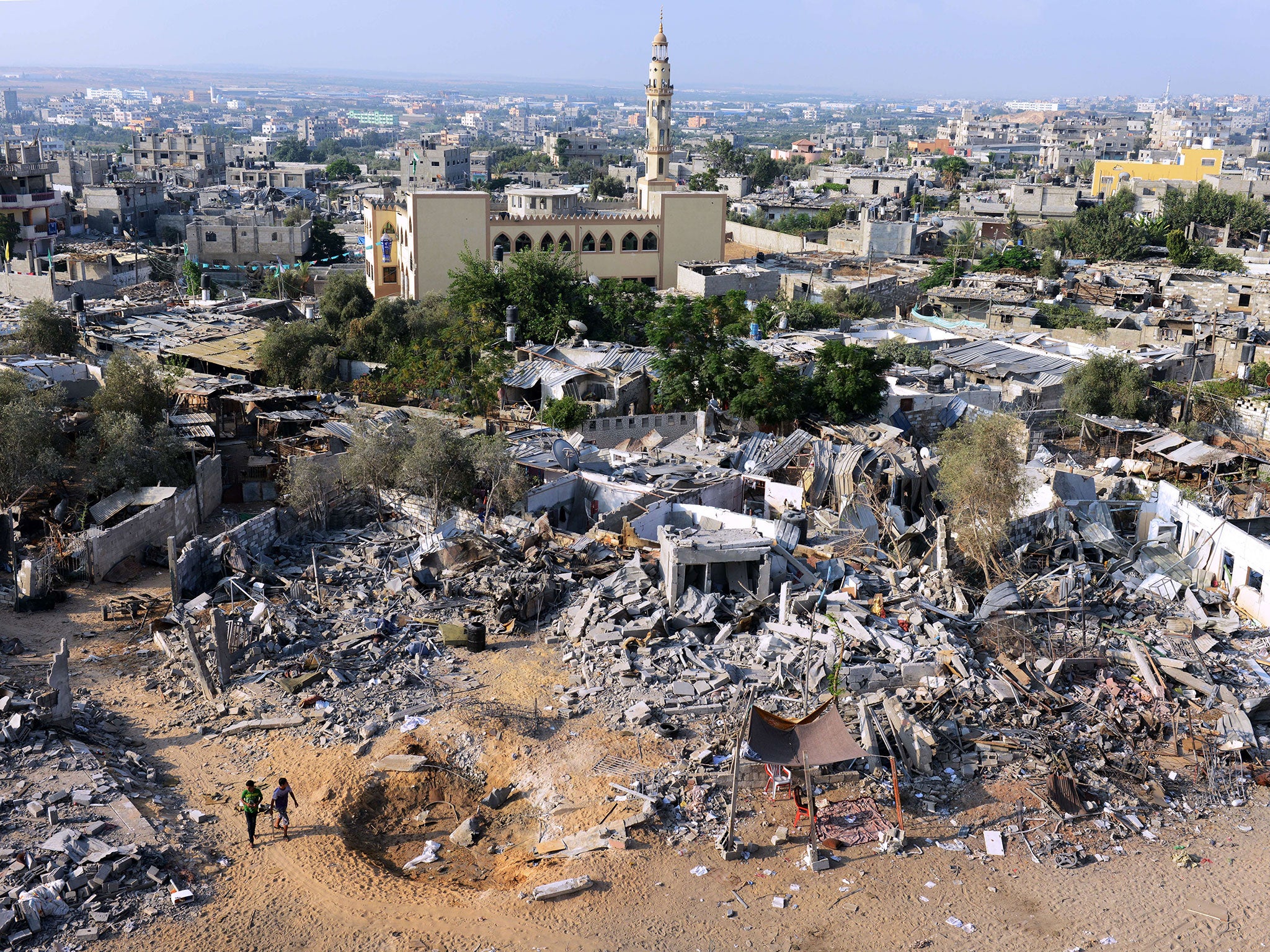 Two boys walk past destroyed homes in northern Gaza, close to the border with Israel, just before the whole region was shaken by violence and then relieved by a new ceasefire last night