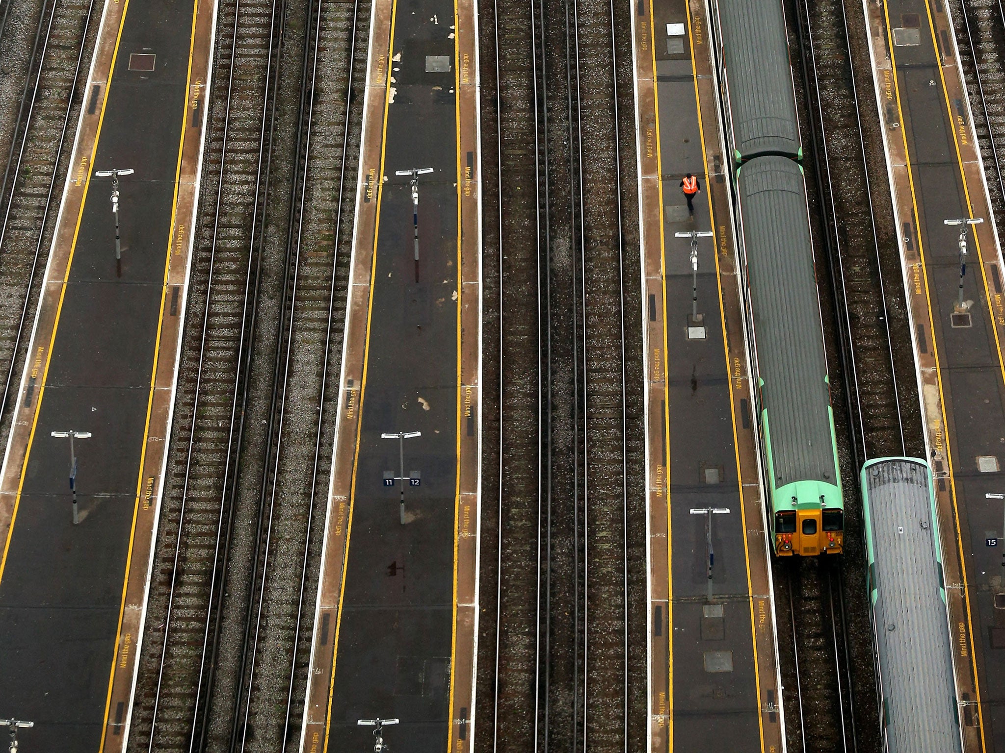File: A railway worker walks along the platform of London Bridge Station, seen from the 69th floor of The Shard on October 26, 2012