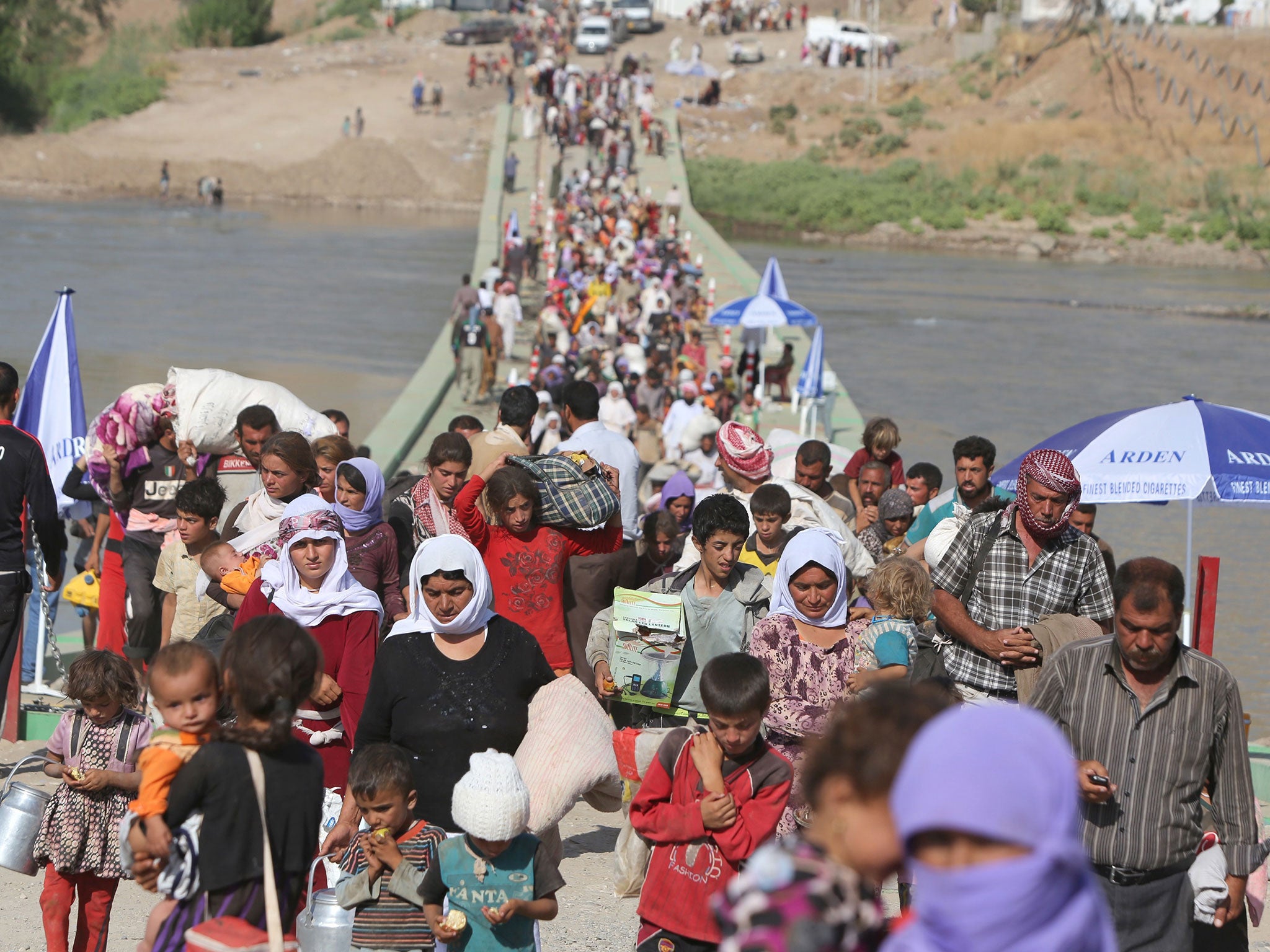 Displaced Iraqis from the Yazidi community cross the Syrian-Iraqi border along the Fishkhabur bridge over the Tigris River at the Fishkhabur crossing, in northern Iraq, on August 13, 2014. At least 20,000 civilians, most of whom are from the Yazidi commun