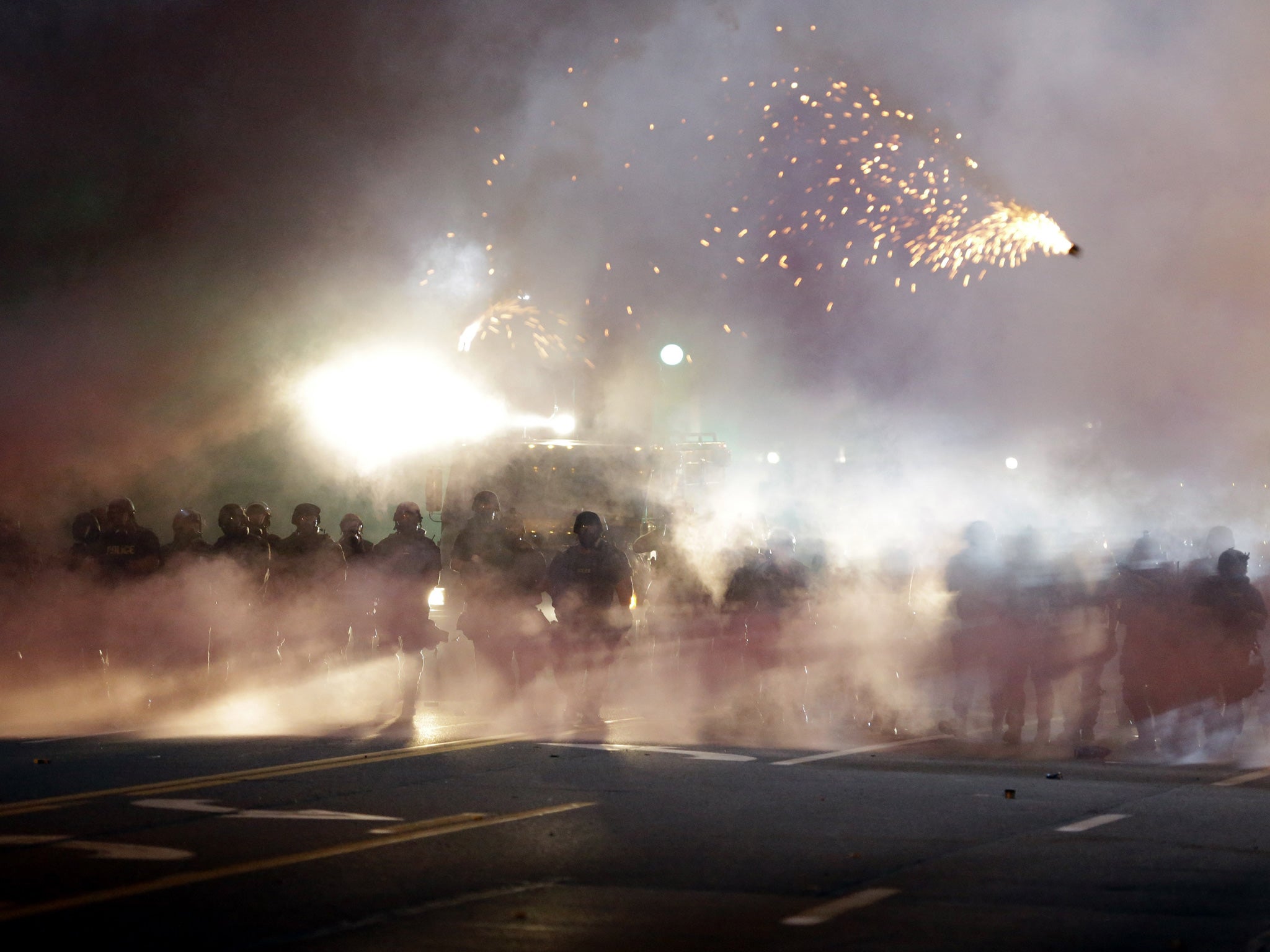 An explosive device deployed by police flies in the air as police and protesters clash Wednesday, Aug. 13, 2014, in Ferguson