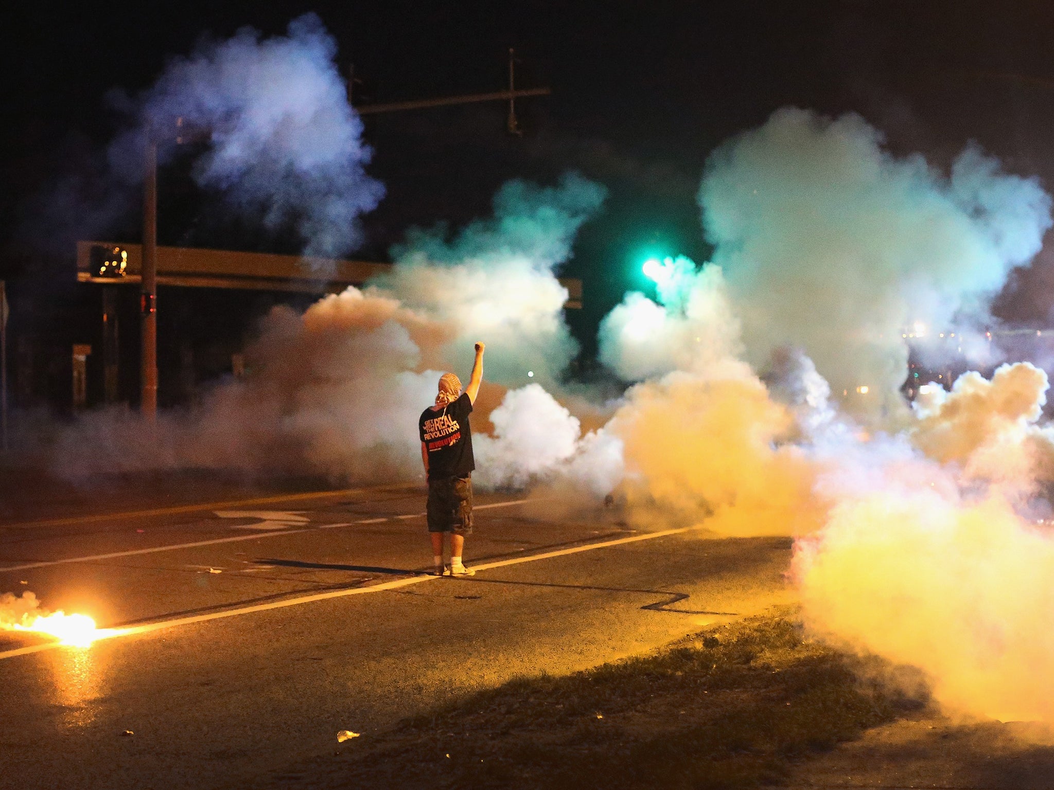 A demonstrator, protesting the shooting death of teenager Michael Brown, stands his ground as police fire tear gas in Ferguson