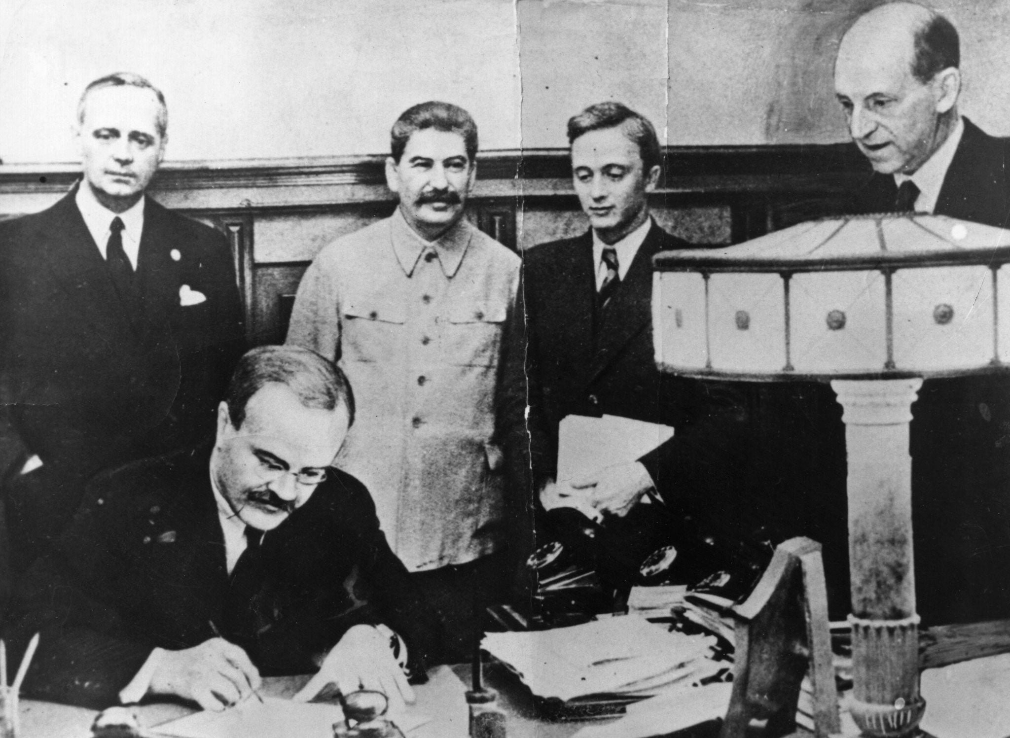 Historic moment: Vyacheslav Molotov, Russian foreign minister, signs the pact between Soviet Russia and Germany in 1939, as Joseph Stalin looks on