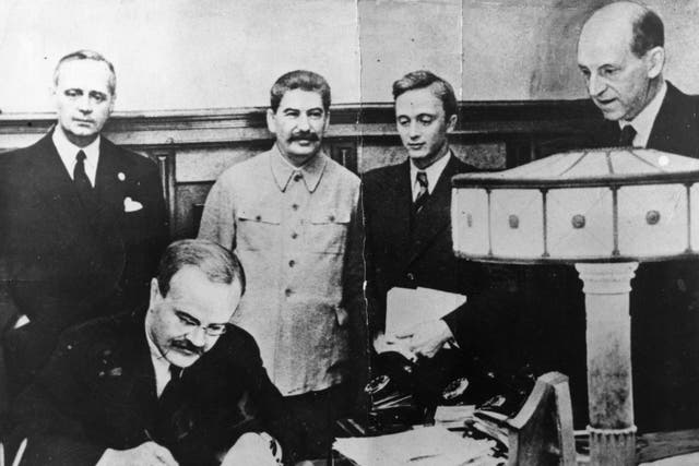 Historic moment: Vyacheslav Molotov, Russian foreign minister, signs the pact between Soviet Russia and Germany in 1939, as Joseph Stalin looks on