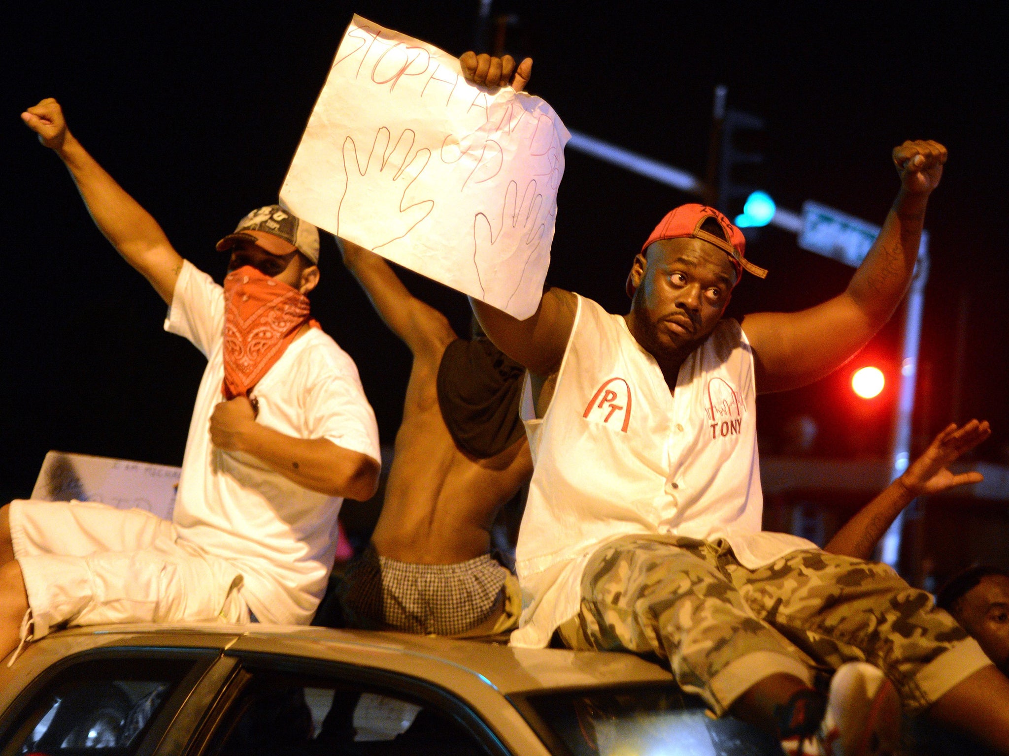 Protesters ride on top of a car as they gather on West Florissant Avenue in Ferguson, Missouri