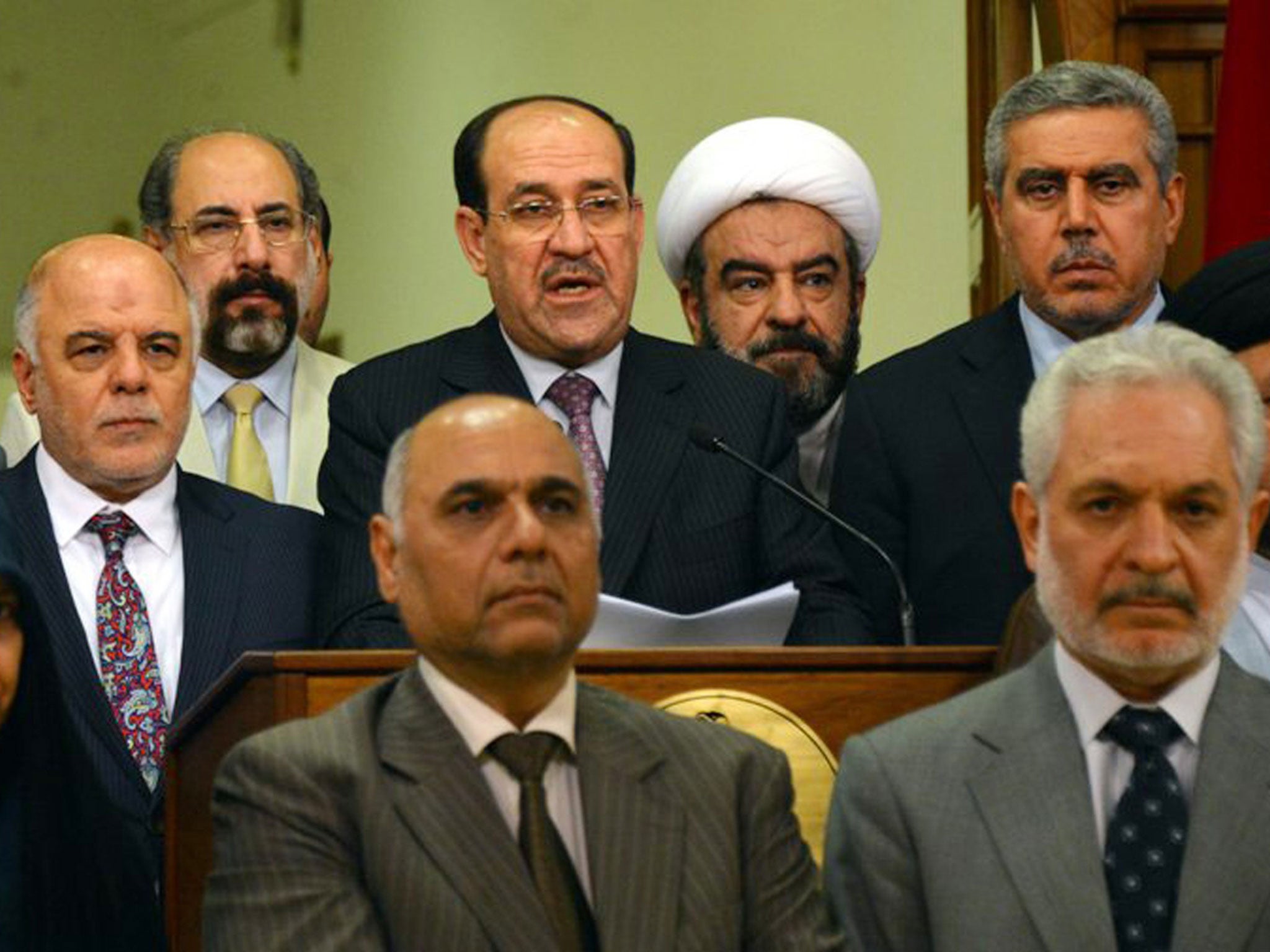 Nouri al-Maliki, surrounded by Iraqi lawmakers, addresses the nation to announce he is stepping down as PM