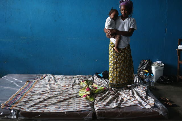 A mother and child stand atop their mattresses in a classroom now used as Ebola isolation ward 
