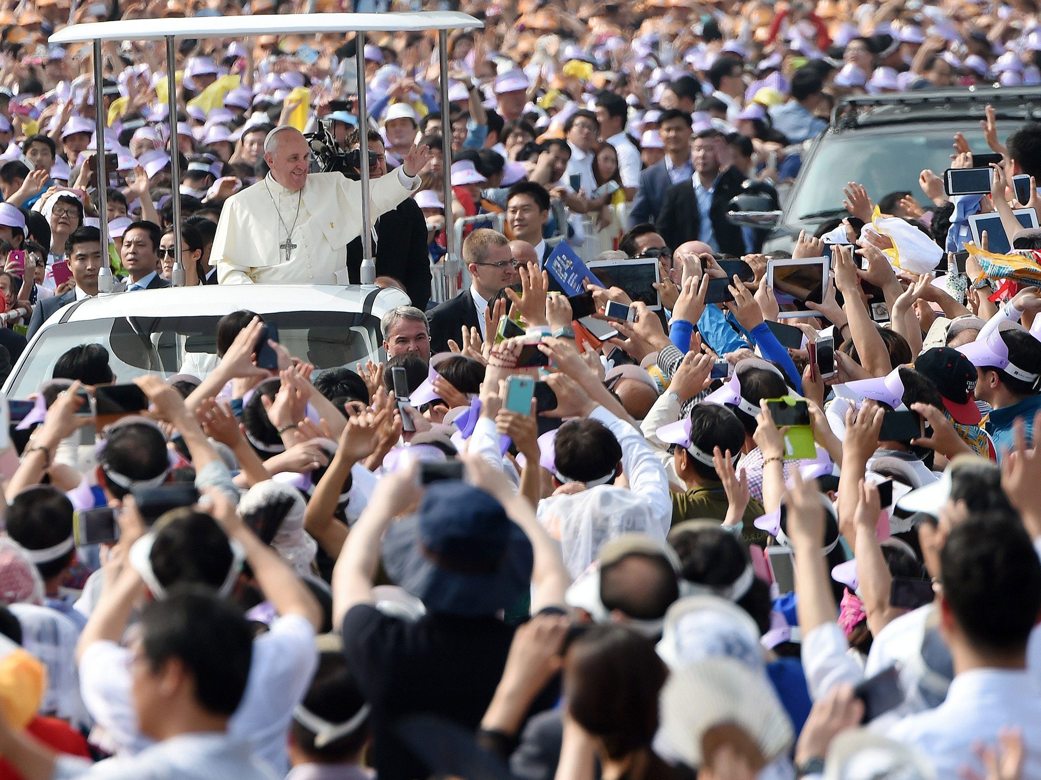 Pope Francis (L, middleground) waves to the crowd from the popemobile prior to a mass, in Seoul, South Koera, 16 August 2014.