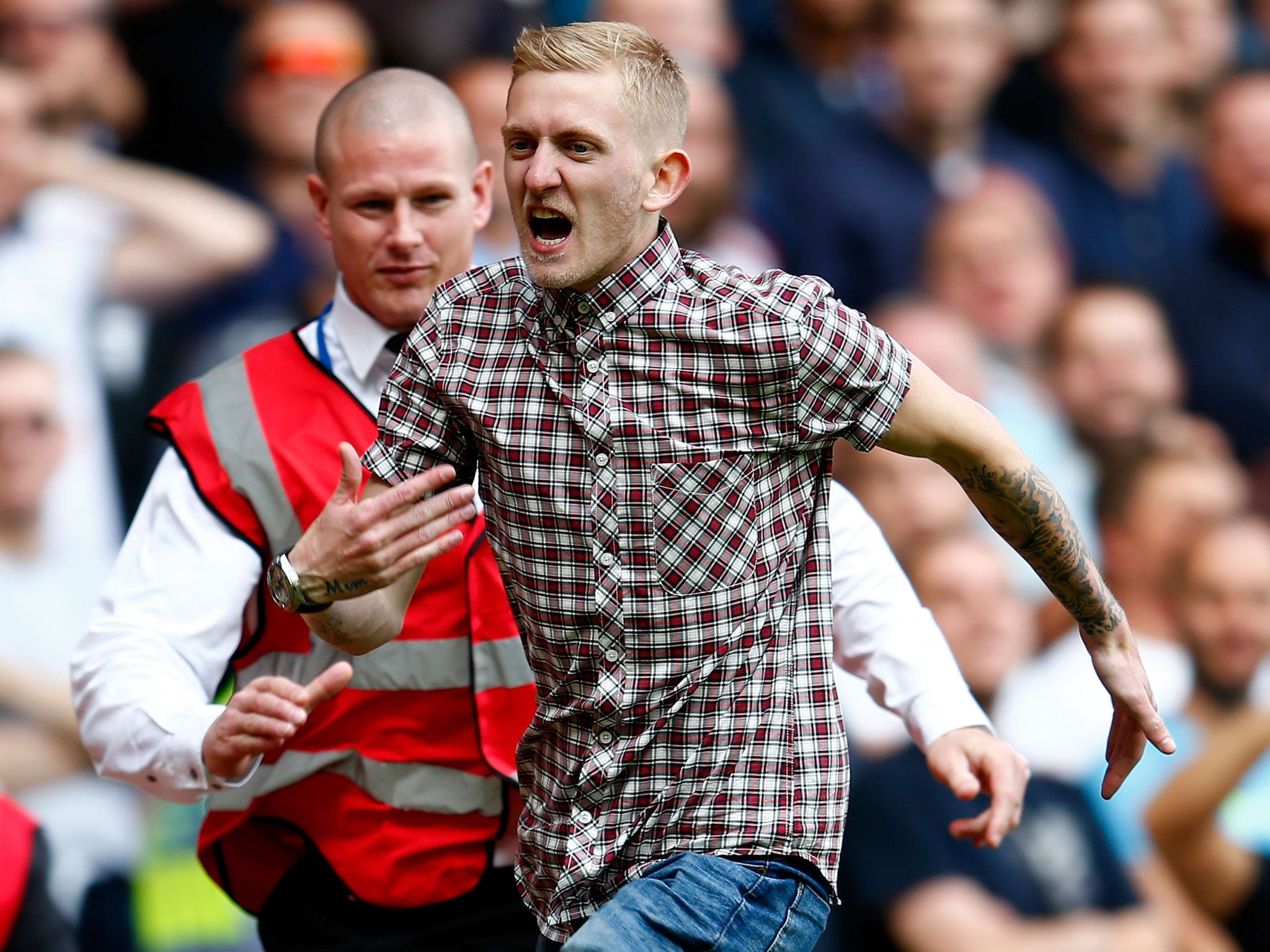 A pitch invader is chased by stewards during West Ham v Tottenham