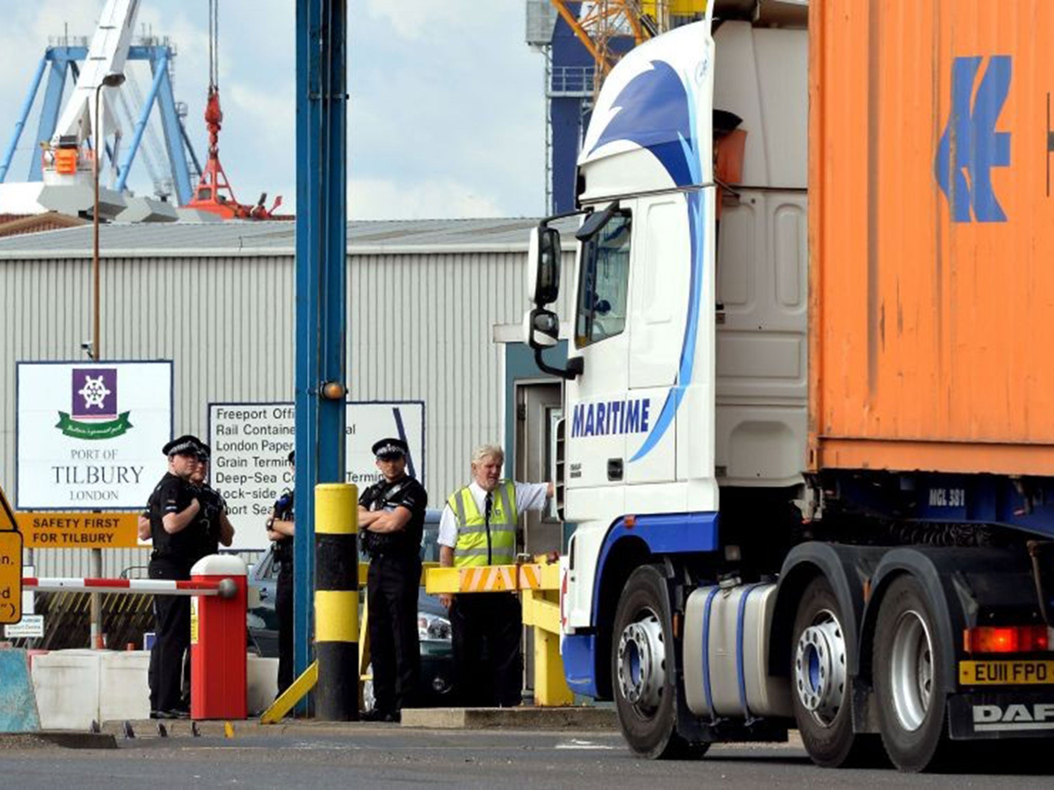 A group of Police Officers stand by the main entrance to Tilbury Docks in Essex, where a shipping container was found with 31 illegal immigrants inside