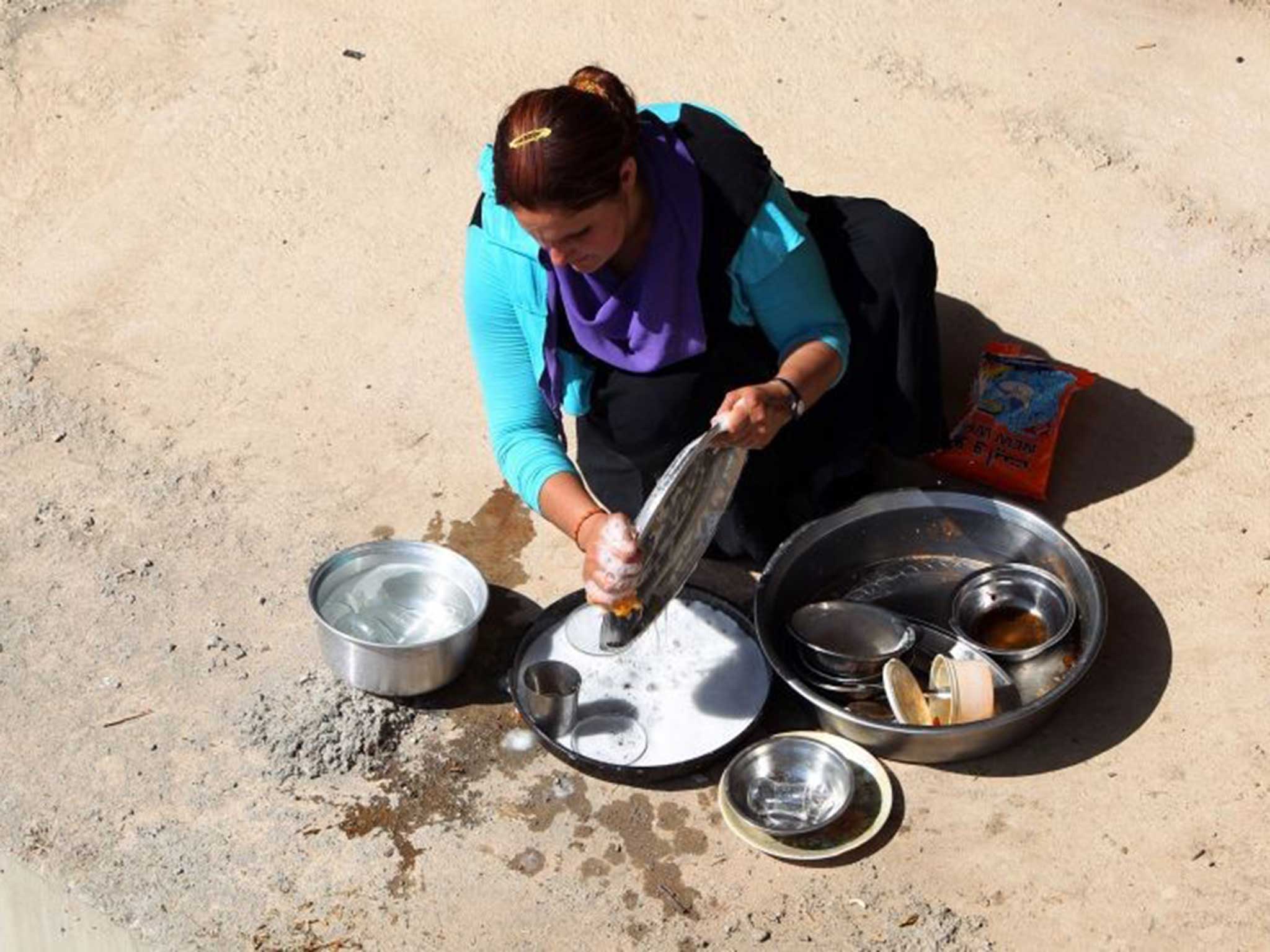 An Iraqi Yazidi woman, who fled her home when Islamic State militants attacked the town of Sinjar, cleans dishes