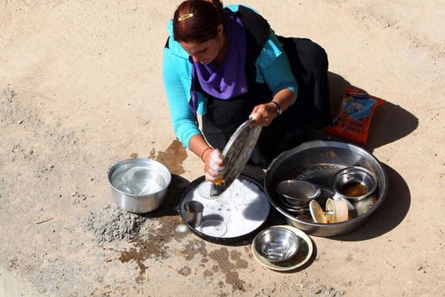 An Iraqi Yazidi woman, who fled her home when Islamic State militants attacked the town of Sinjar, cleans dishes
