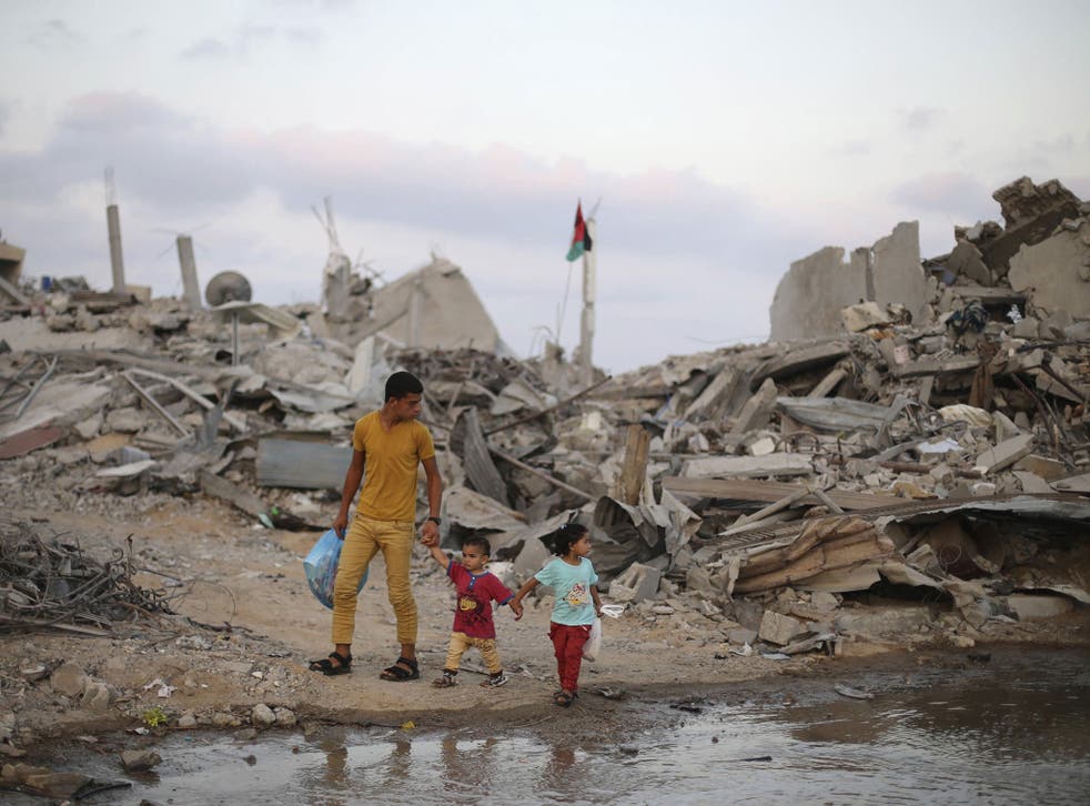 Palestinians walk next to the ruins of houses on the fifth day of ceasefire in Khan Younis in the southern Gaza Strip 
