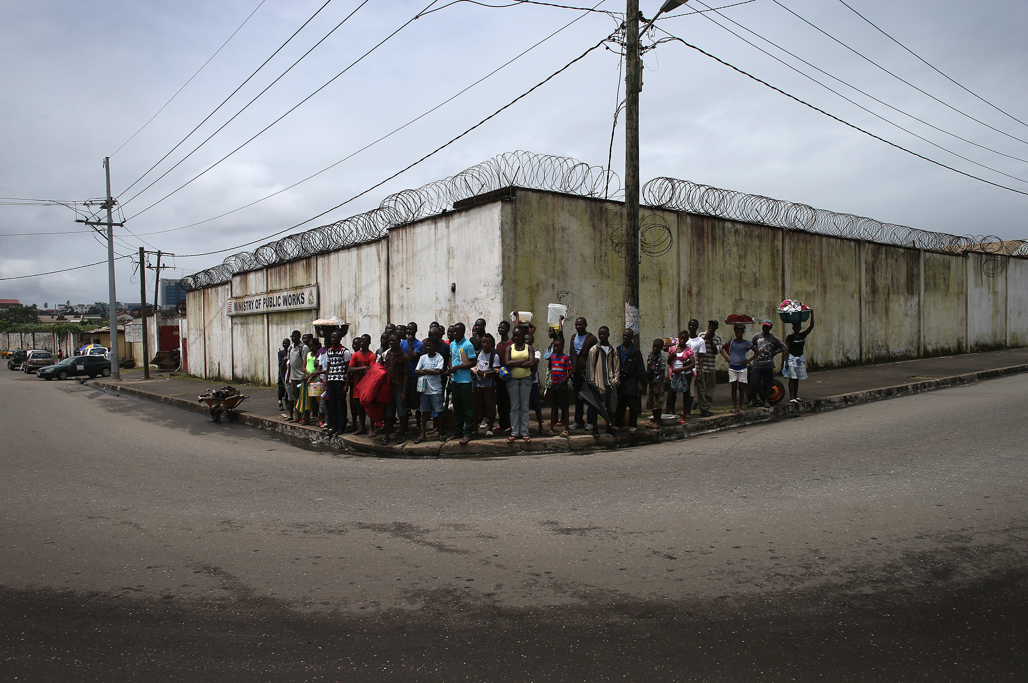 Locals watch public health advocates stage street performances at an Ebola awareness and prevention event in Monrovia