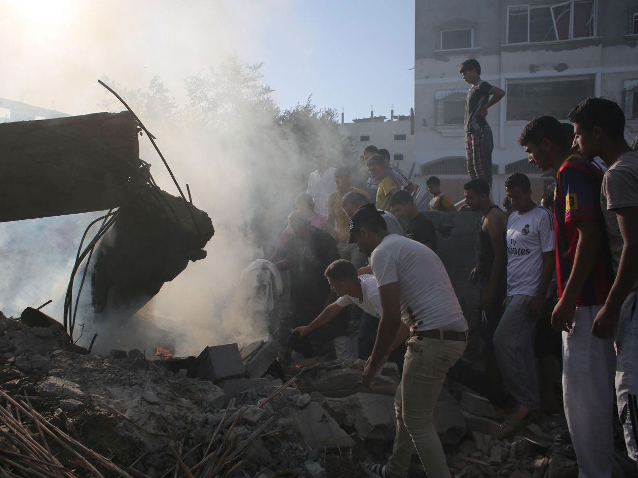 Palestinian men gather at a destroyed house on August 20, 2014, targeted late last night in an Israeli airstrike in Rafah