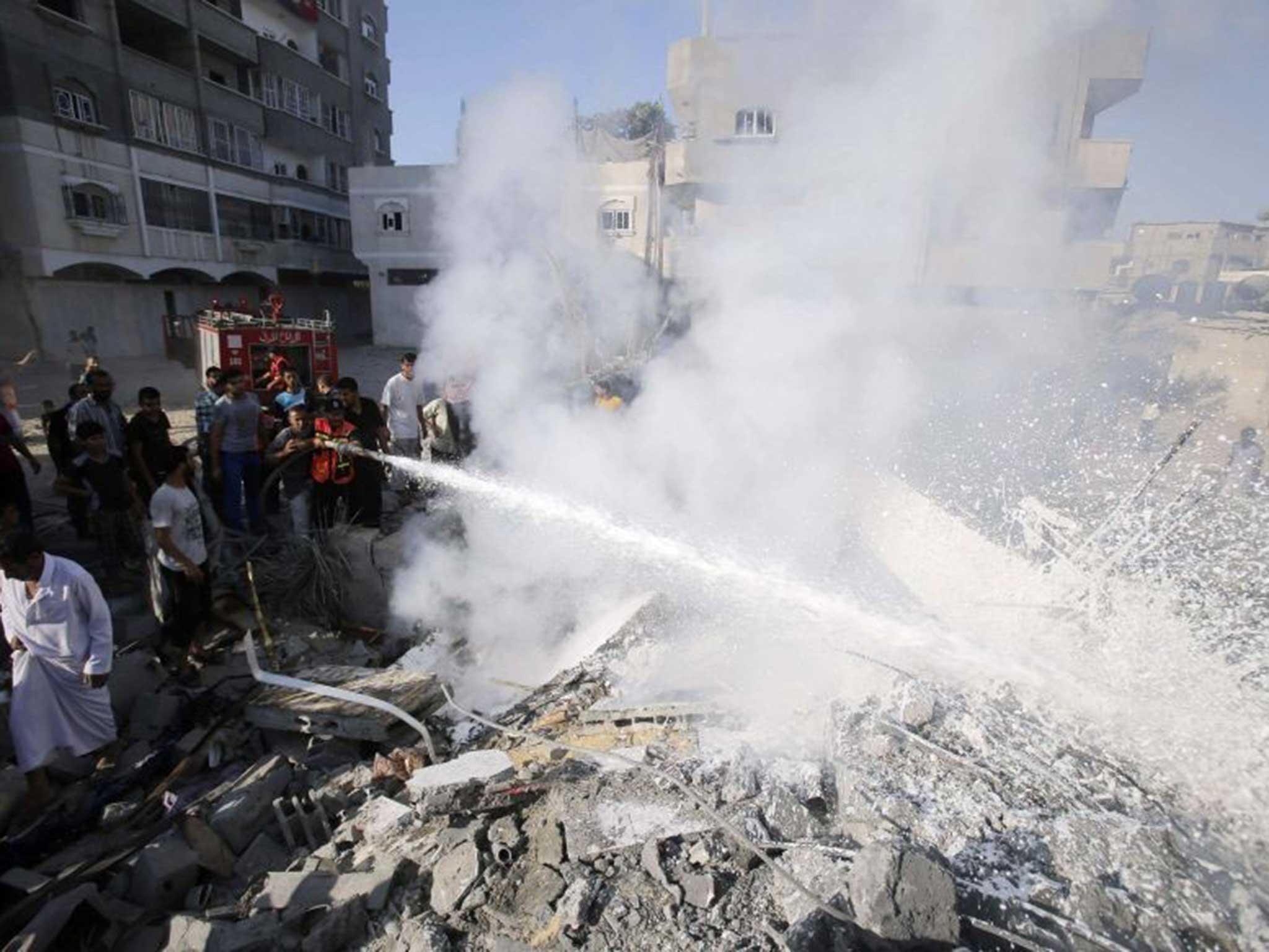 Palestinians help to put out a fire from the rubble of a house, which witnesses said was destroyed in an Israeli air strike, in Rafah 