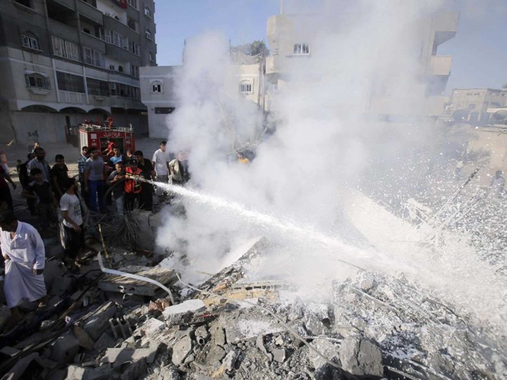 Palestinians help to put out a fire from the rubble of a house, which witnesses said was destroyed in an Israeli air strike, in Rafah