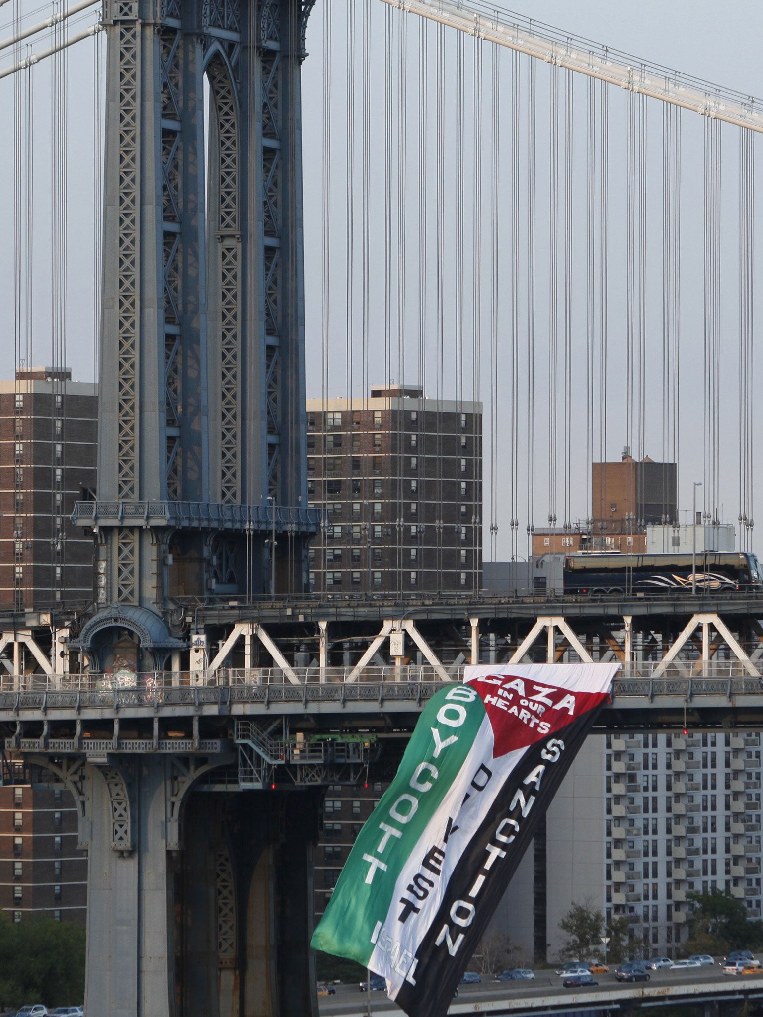 Demonstrators hang a protest flag from the south side of the Manhattan Bridge as a pro-Palestinian rally (not pictured) makes its way across the nearby Brooklyn Bridge