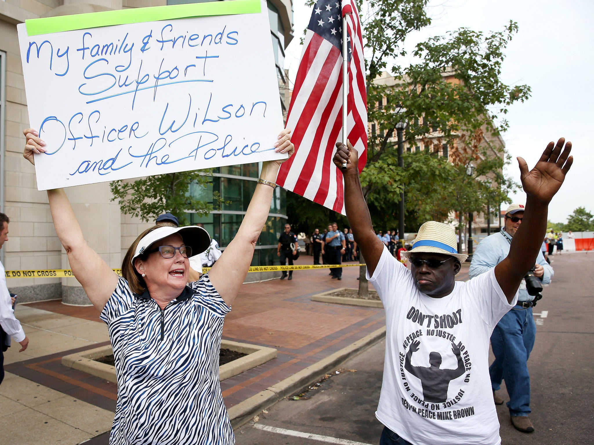 Patty Canter (L) holds a sign reading, " My Family & Friends Support Officer Wilson and the Police"