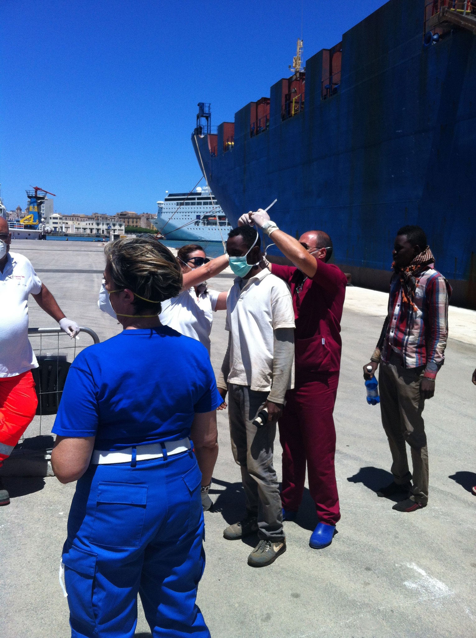 African migrants are inspected by Italian officials as they leave the ship Tichy in the port of Trapani