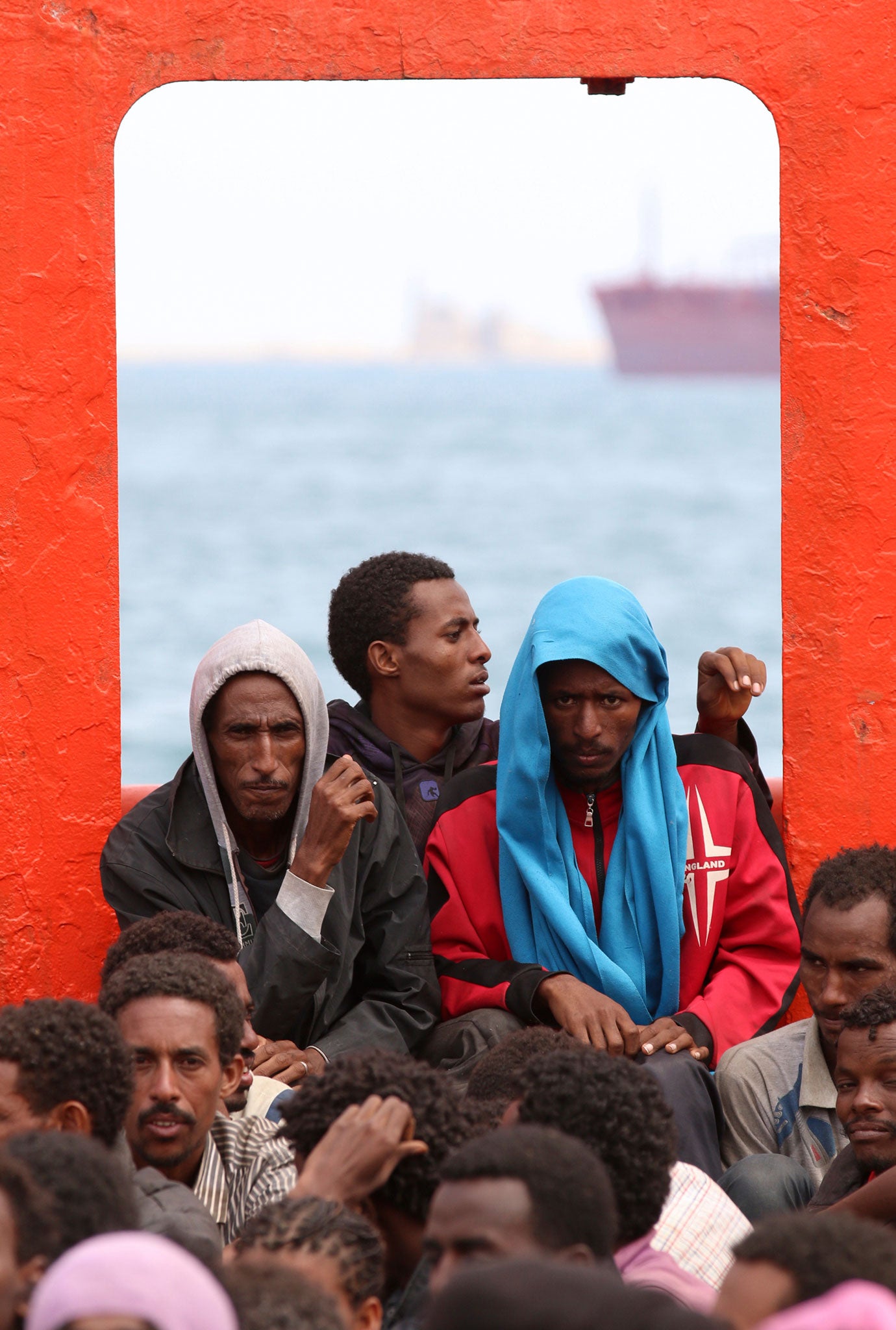 Migrants wait aboard a navy ship before disembarking in a Sicilian harbour
