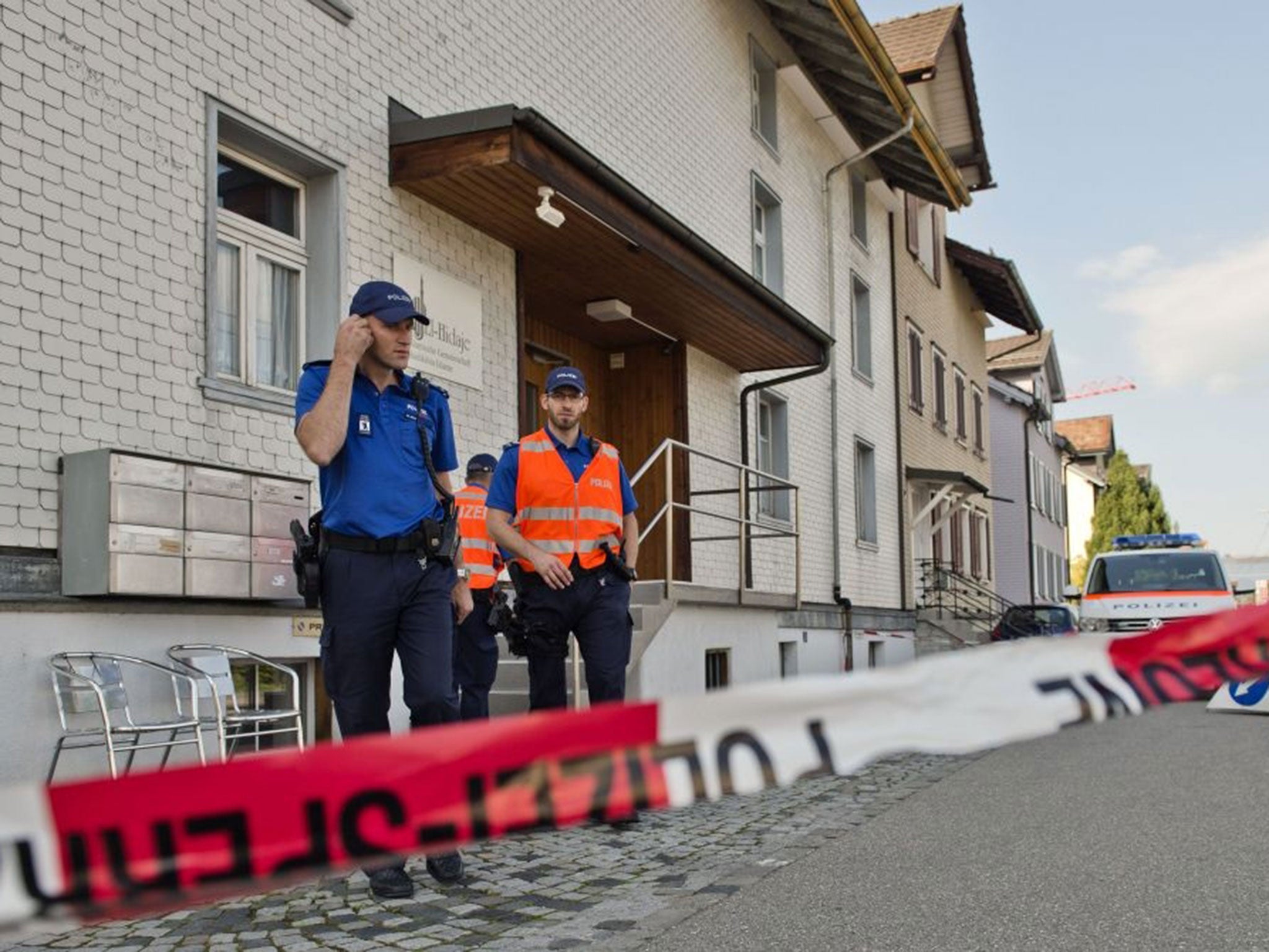 Police officers stand near the mosque where one person was killed during a shooting