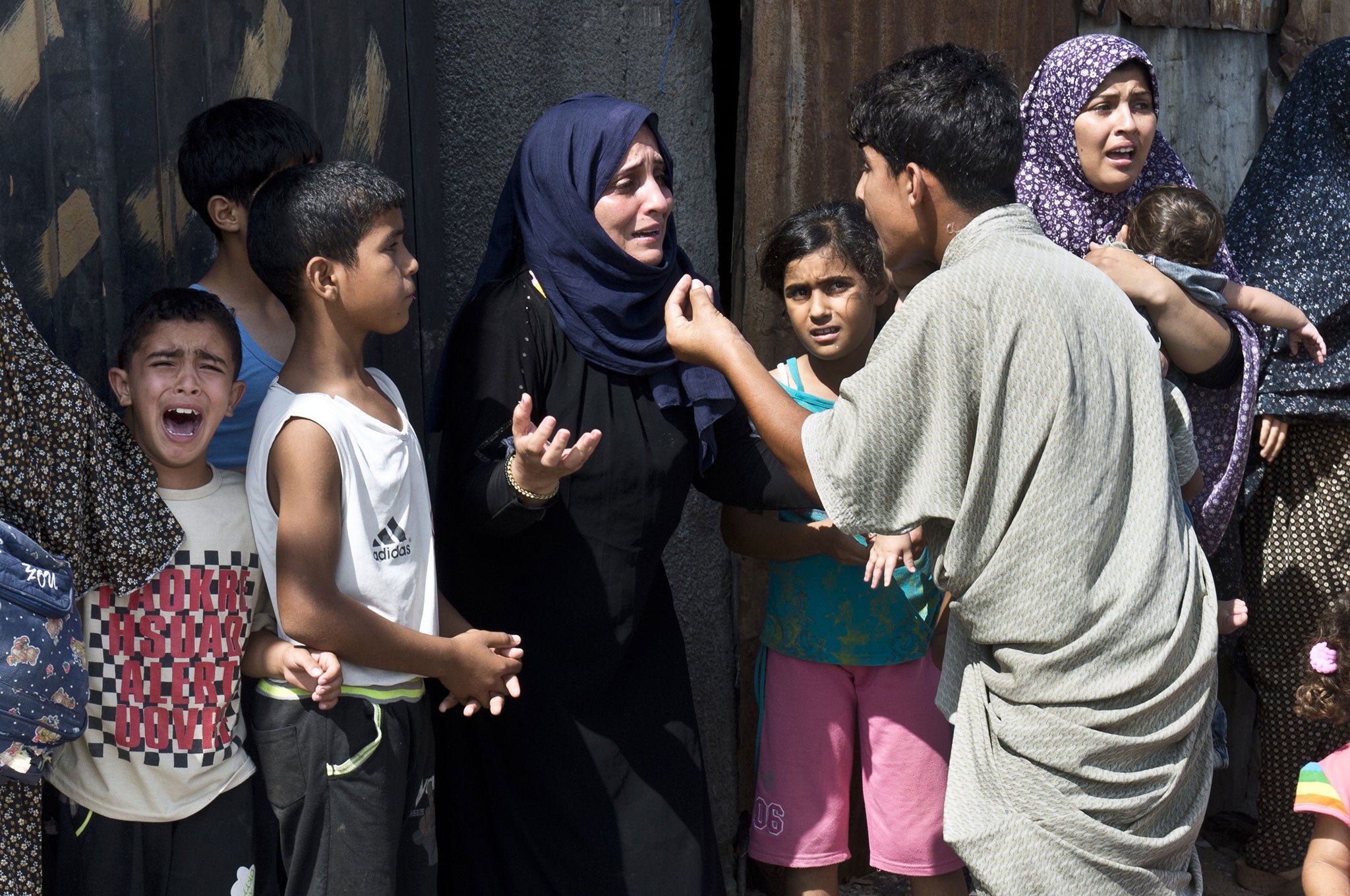 A Palestinian boy (left) cries in panic as other members of his family discuss what to do