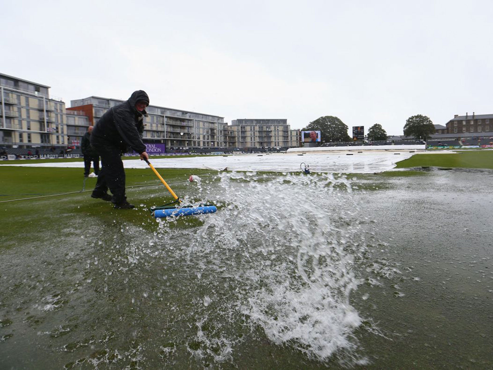 The Bristol ground staff try in vain to remove water from the outfield on Monday