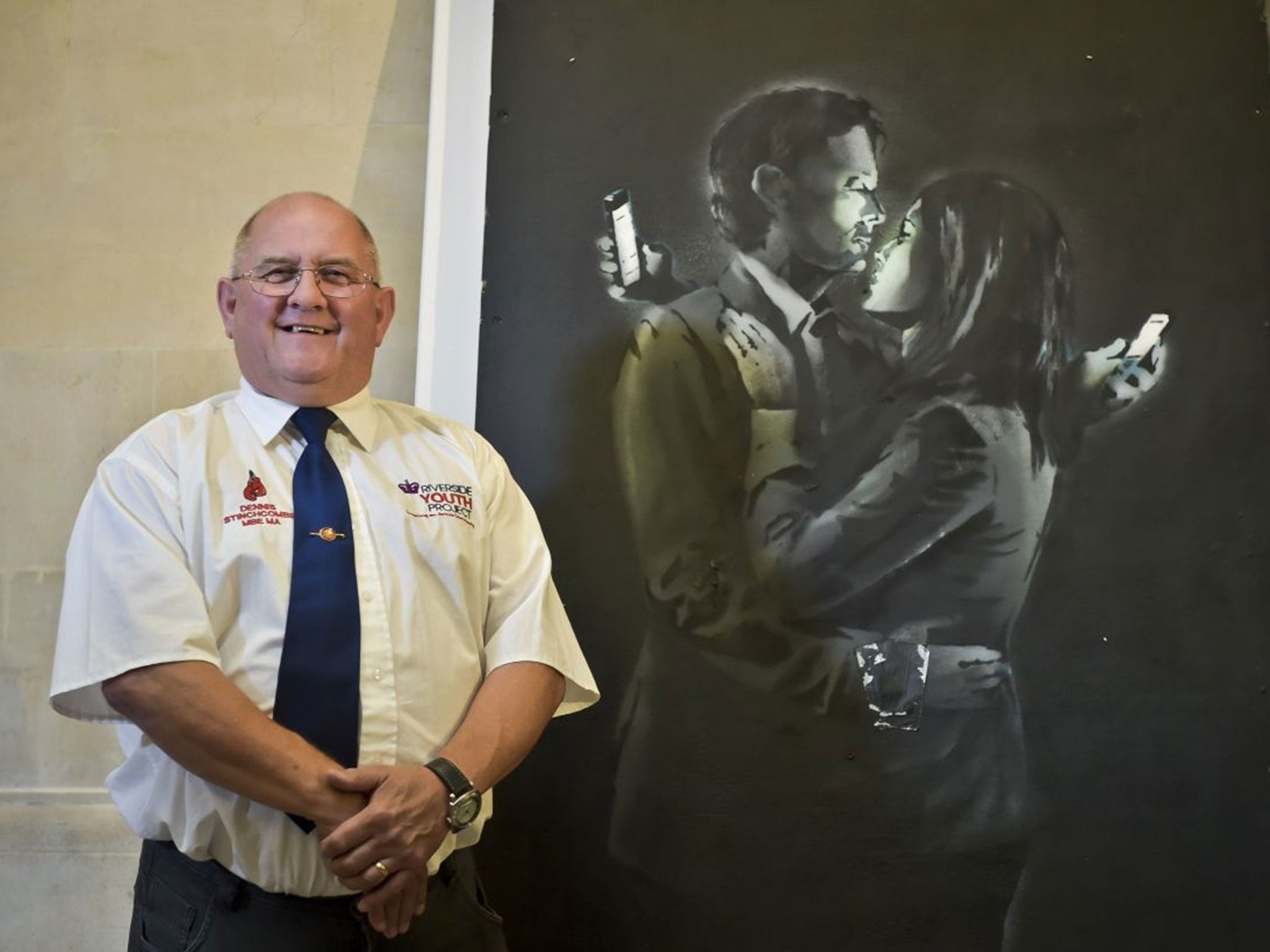 Dennis Stinchcombe, of Broad Plain Boys' Club in Bristol, by a Banksy artwork, titled 'Mobile Lovers', where the sale and handover have been completed at the Bristol Museum & Art Gallery, where it was on display to the public.