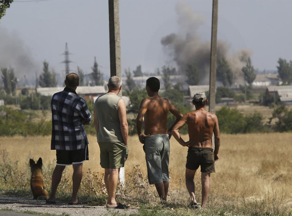 Local residents watch as smoke rises, during shelling, in the town of Novoazovsk, eastern Ukraine