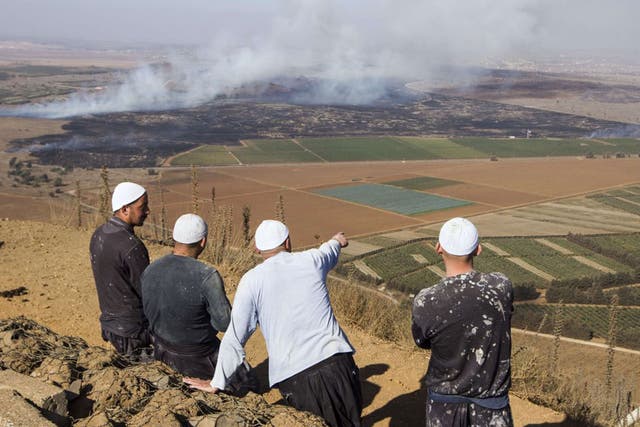 Druze men in the Golan Heights look on as smoke rises from the fighting between forces loyal to President Assad and rebels over the control of the Quneitra border crossing