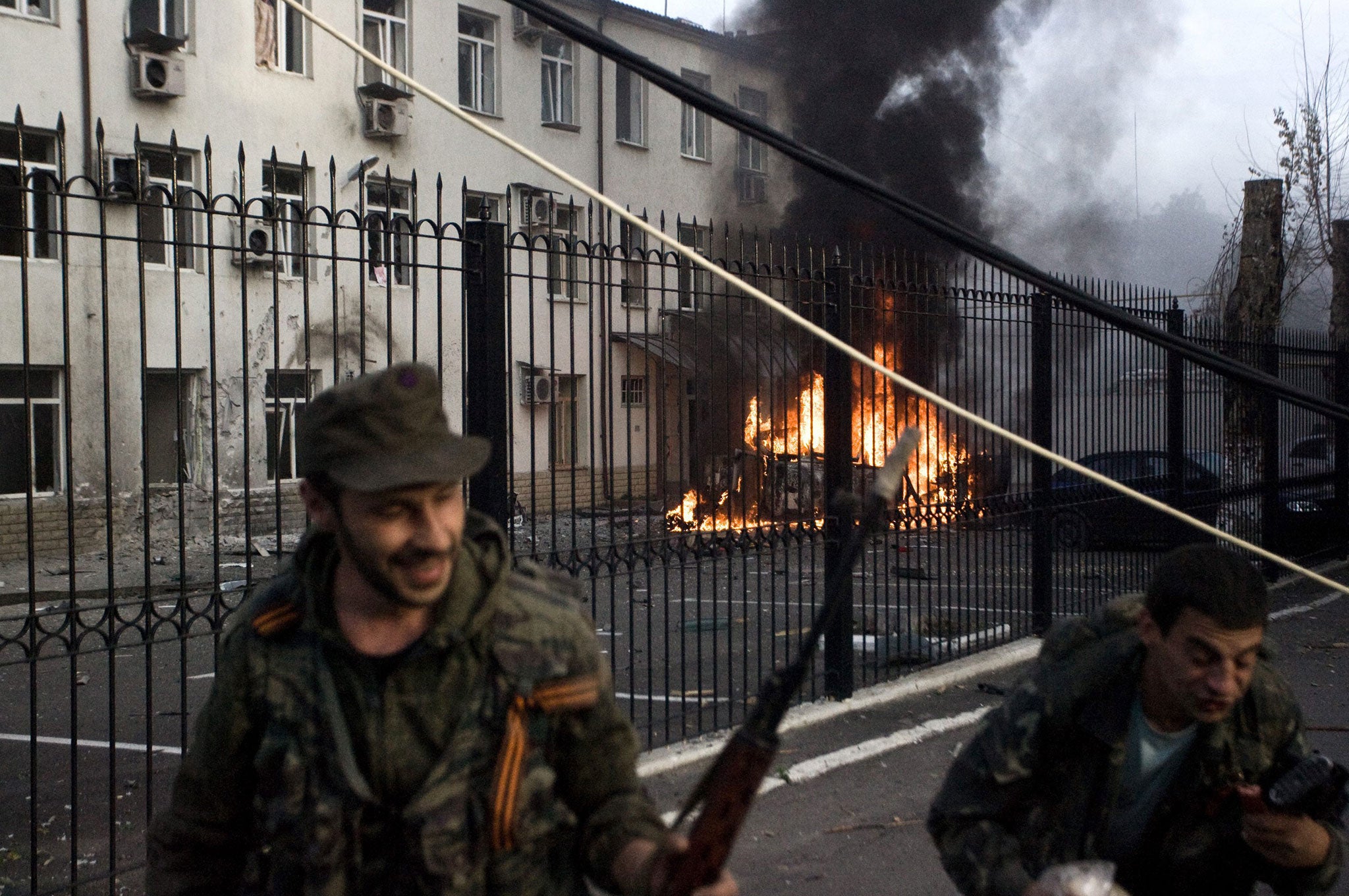 Pro-Russian separatist troops run away from a burning car after Ukranian army shelling in Donetsk, Ukraine