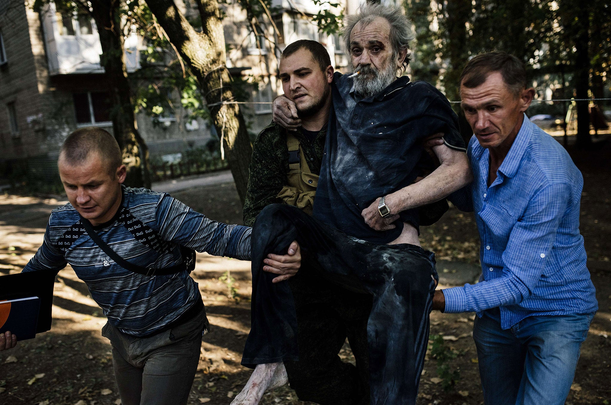 Men carry a wounded elderly man to safety after a shelling in the main separatist stronghold Donetsk