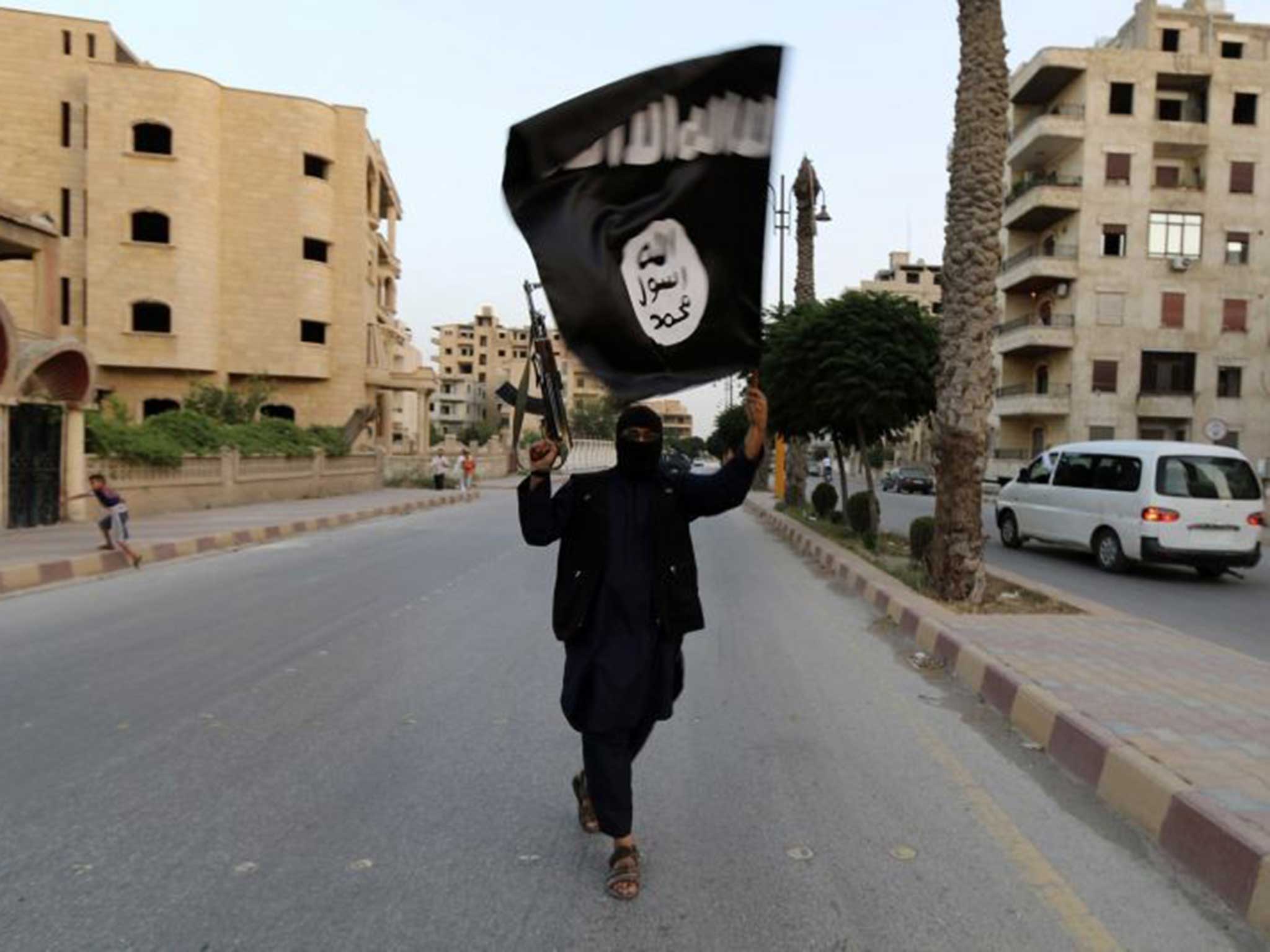 A masked fighter brandishes the IS flag