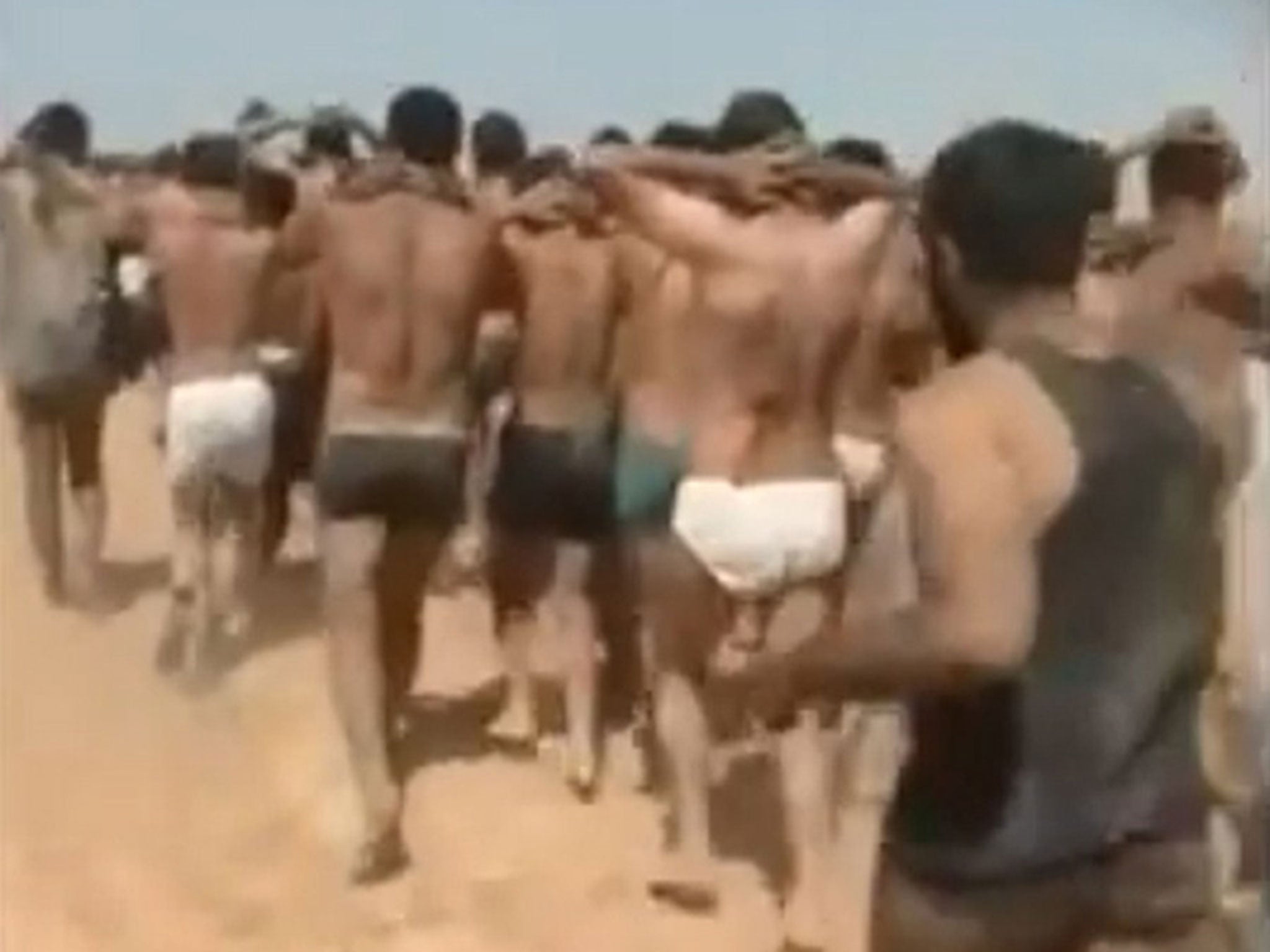 The men being marched barefoot in the desert