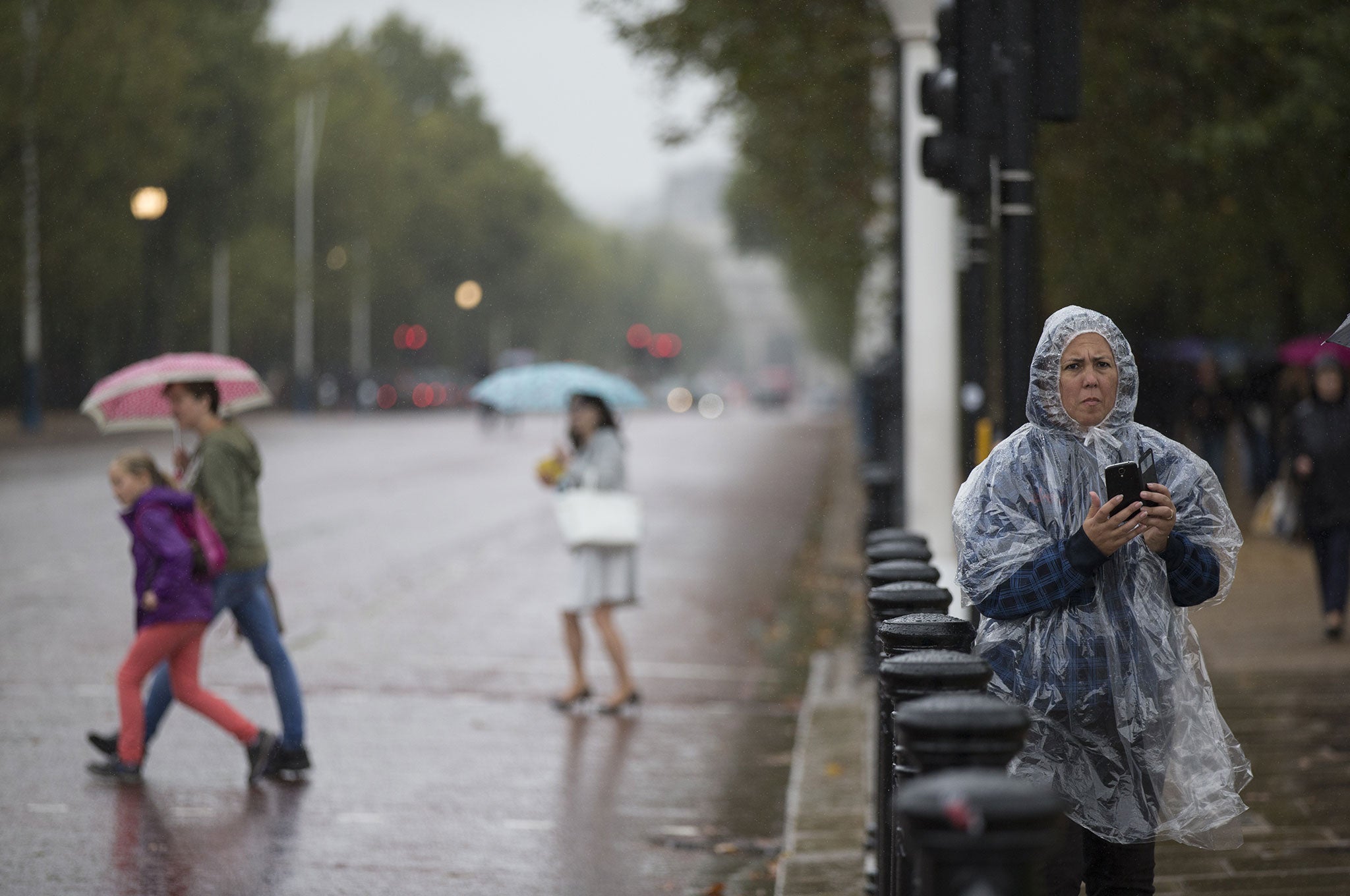 Sightseers admire the area surrounding Buckingham Palace during poor weather in London, England