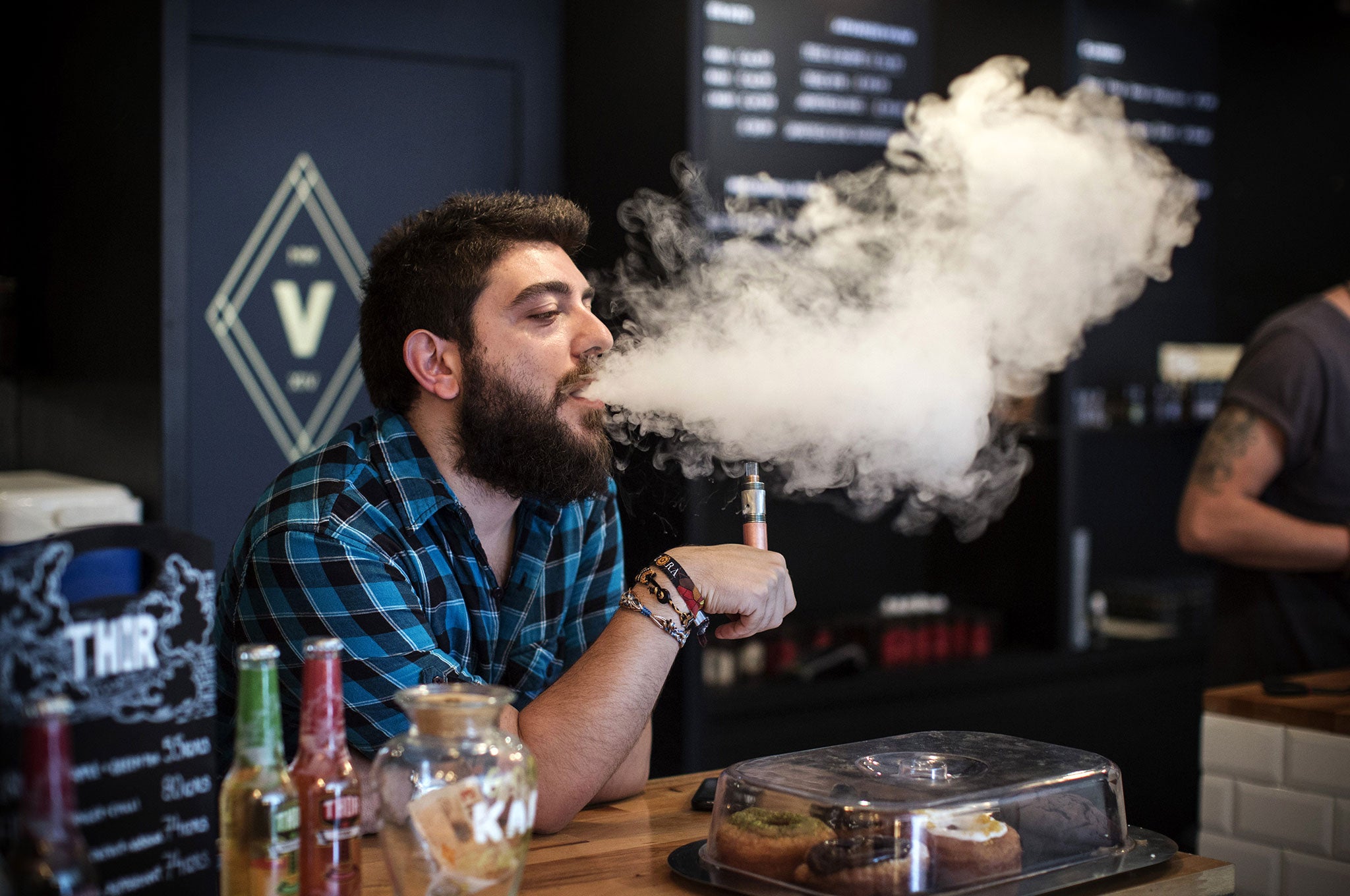 Vape Lab employee Leonardo Verzaro uses an E-Cigarette while working in London. The Department of Health have ruled out the outlawing of 'e-cigs' in enclosed spaces in England, despite calls by the World Health Organisation to do so. WHO have recommended