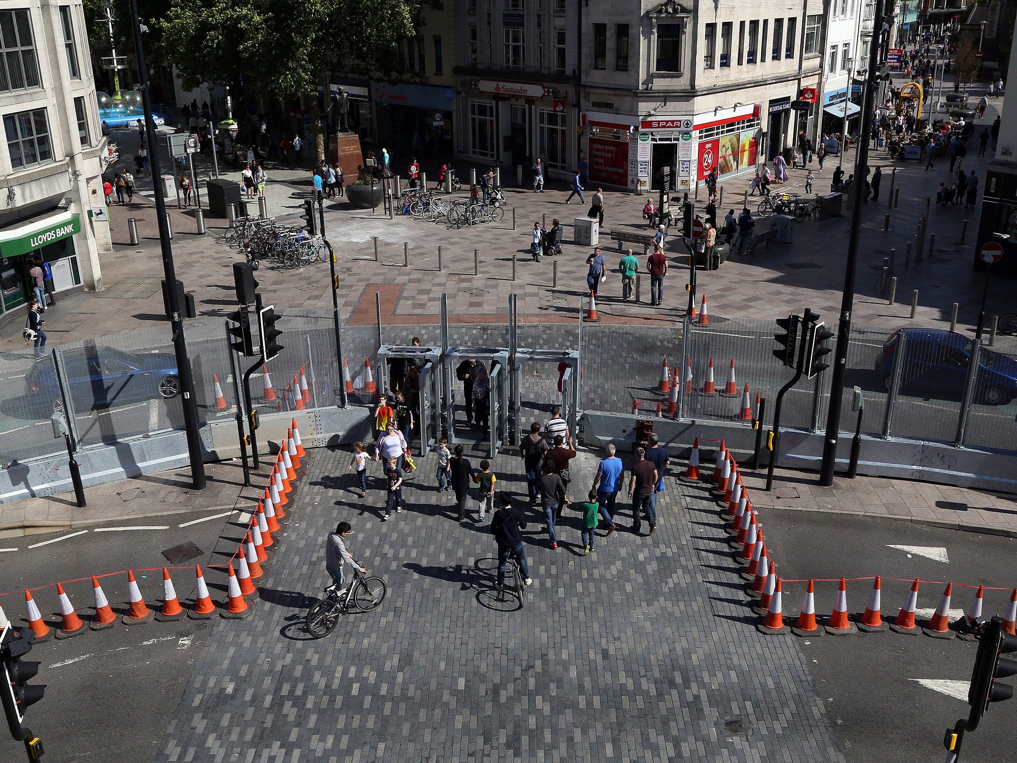 Pedestrians cross the road through a security fence erected around Cardiff Castle