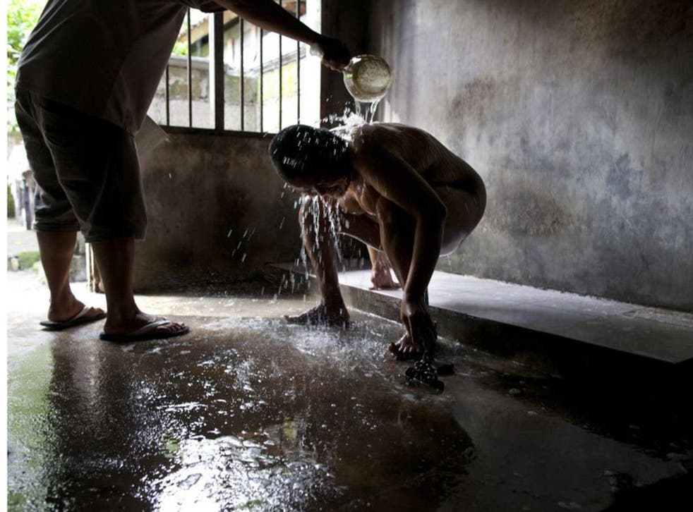 Mentally ill Ketut, 33, being washed by his dad in his room in Indonesia, where he has been chained for eight years 