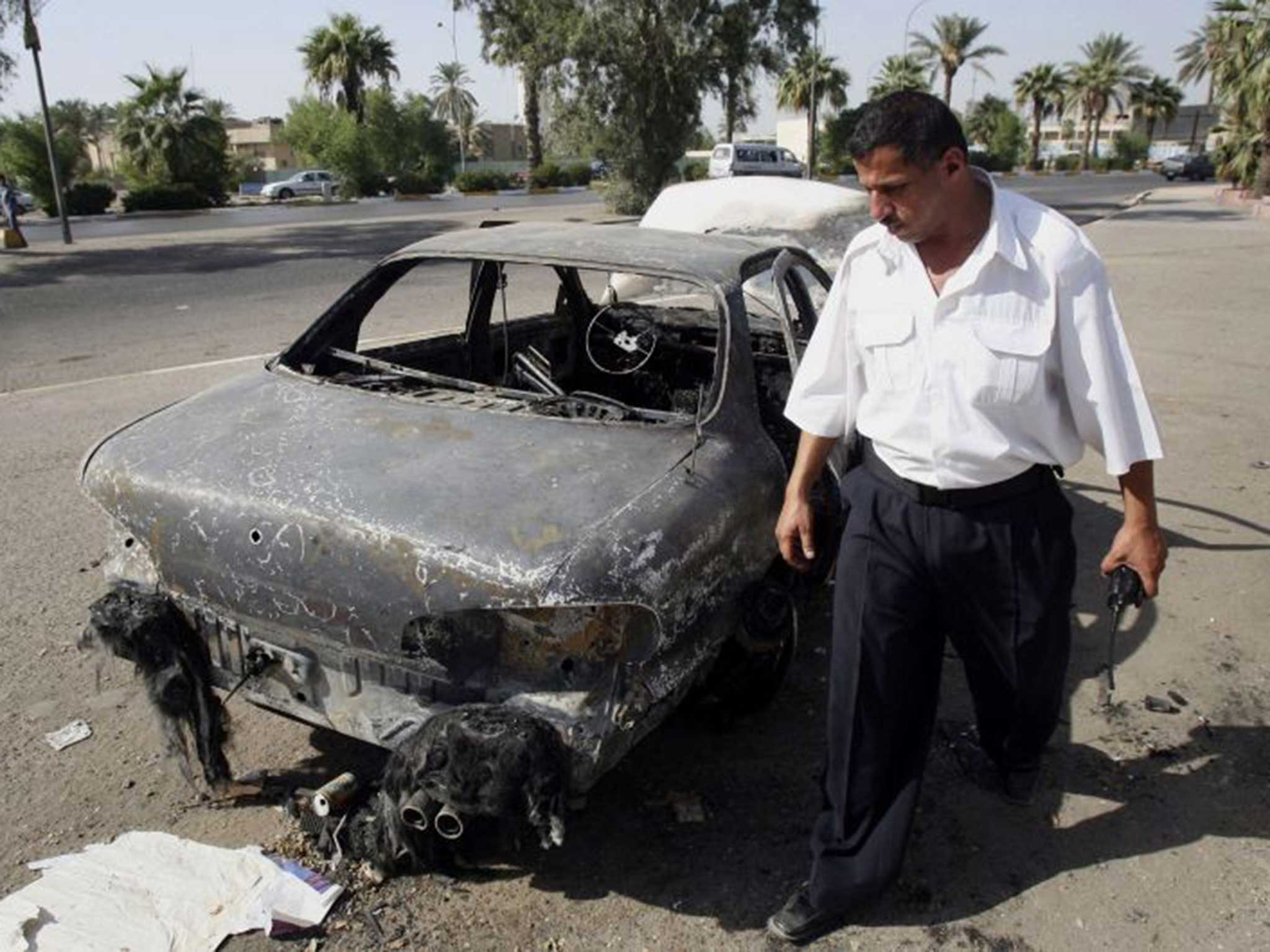 A man inspects a car destroyed by Blackwater operatives
