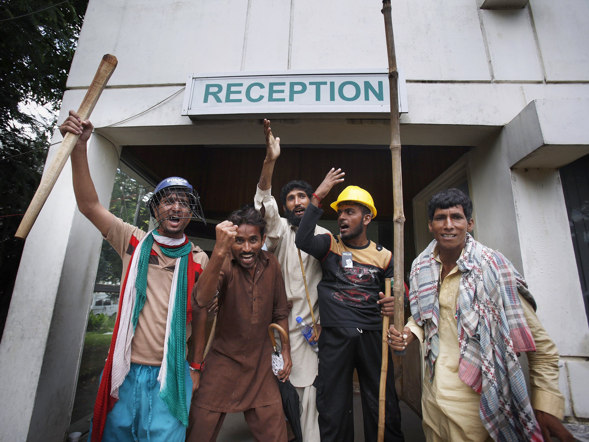 Pakistani protesters hold sticks and chant slogans after intruding the state television building in Islamabad