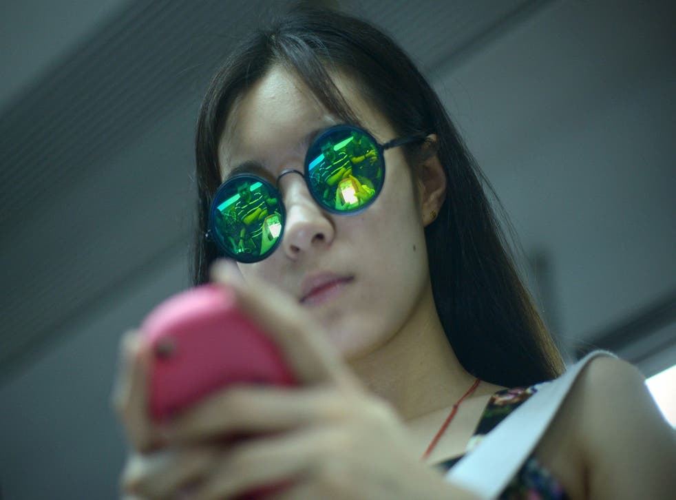 A woman plays a game on her mobile phone on a subway train in Beijing 