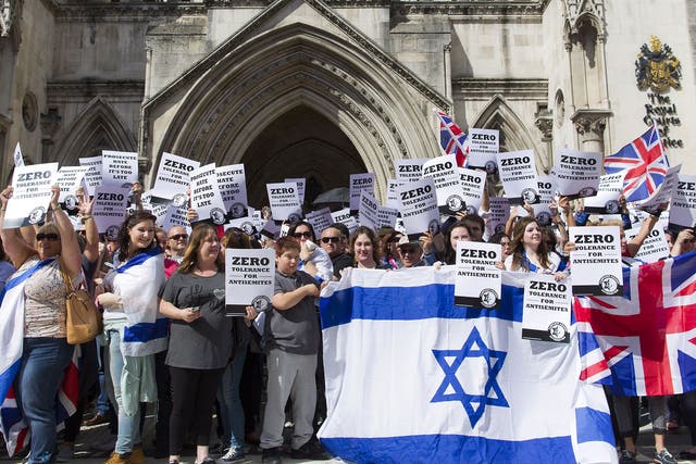 People hold placards and Israeli and Union flags outide the Royal Courts of Justice as Jewish groups rally in London on August 31, 2014, calling for 'Zero Tolerance for Anti-Semitism'.