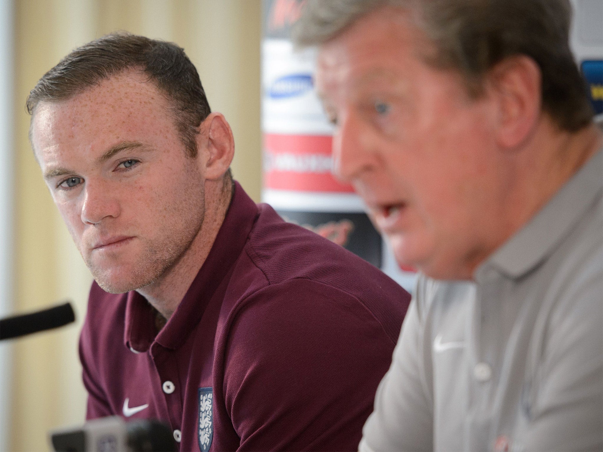 Wayne Rooney watches as England manager Roy Hodgson addresses the media