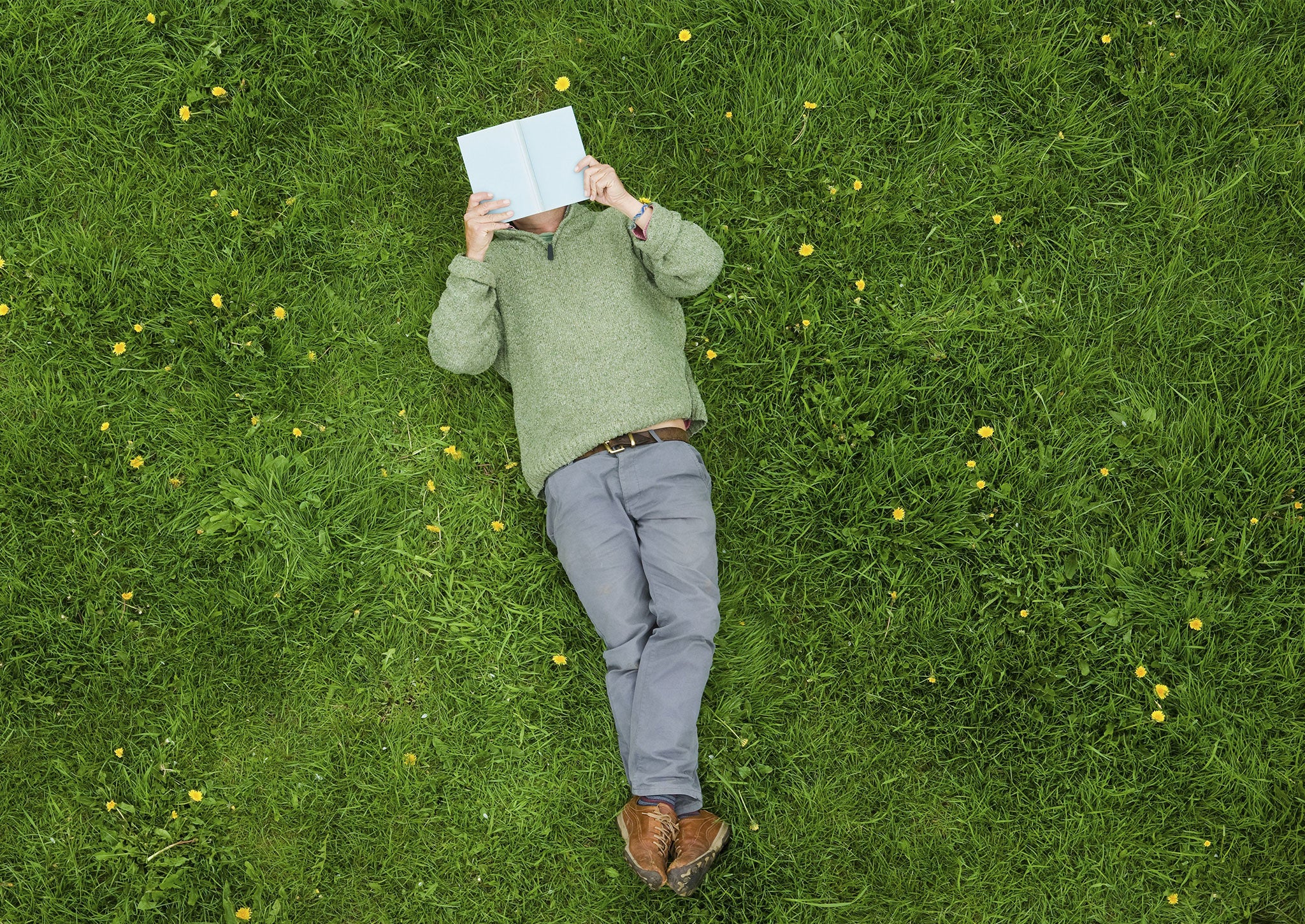 A man lying on his back reads a book
