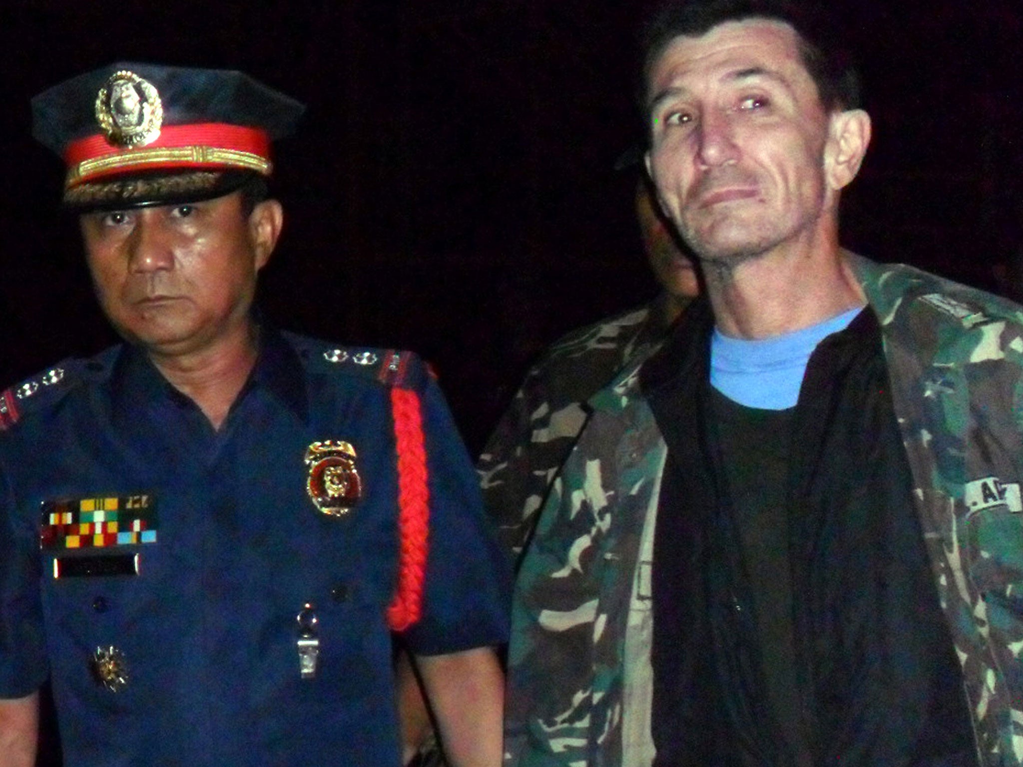 Warren Rodwell is escorted by Philippine police officers as he arrives at a police station in Pagadian City shortly after he was released