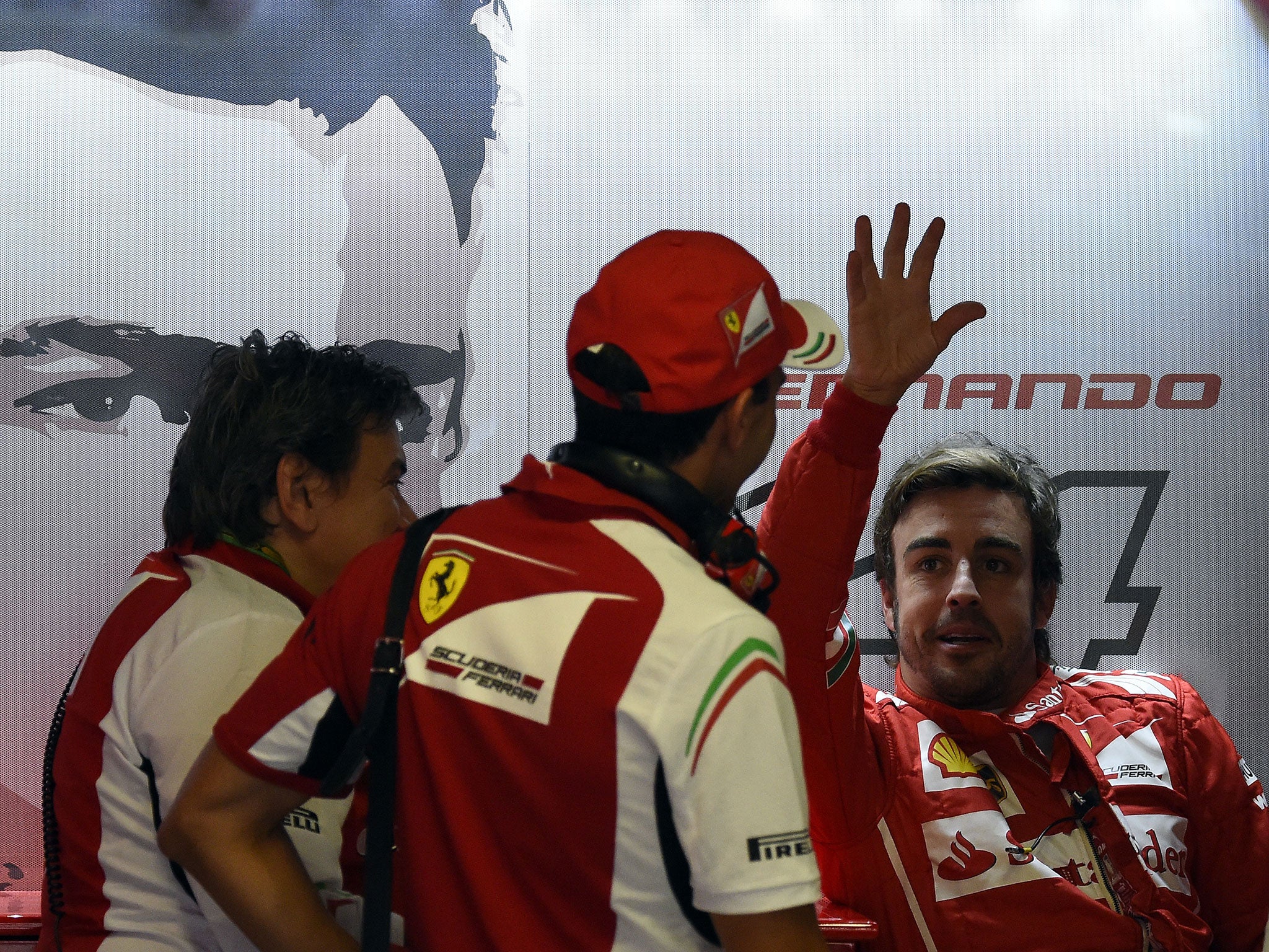 Alonso waves his hand in the air as he talks with his engineers