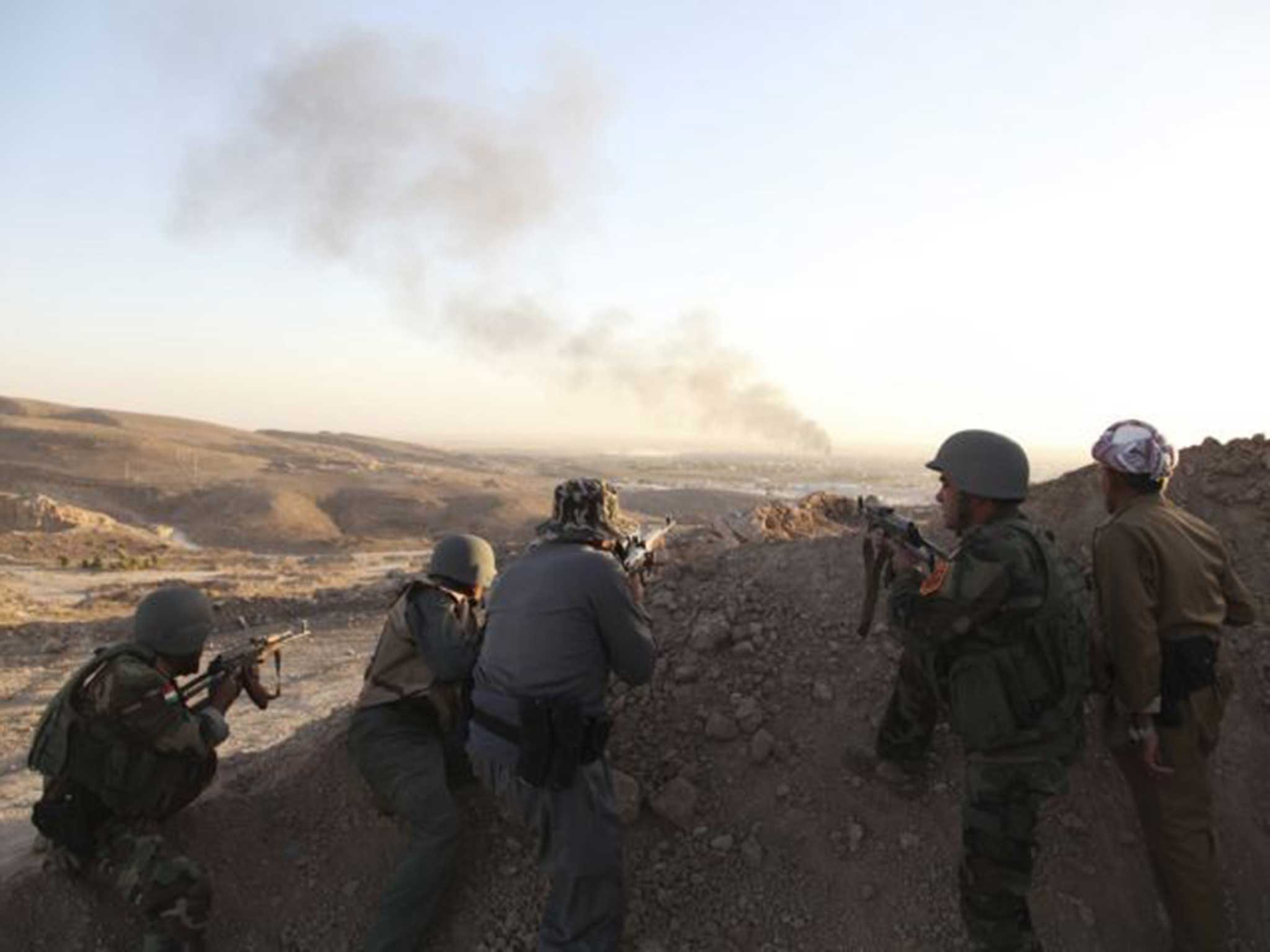 Kurdish Peshmerga troops watch as smoke rises from the town of Makhmour in northern Iraq