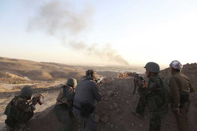 Kurdish Peshmerga troops watch as smoke rises from the town of Makhmour in northern Iraq 