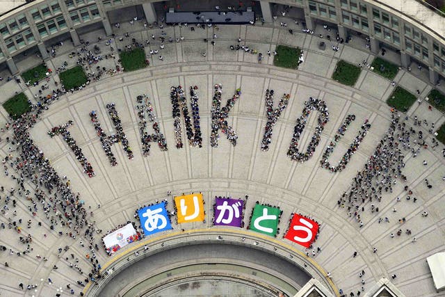An aerial view shows people sitting in formation to the words "thank you" and displaying signs that collectively read "Arigato" (Thank You) during an event celebrating Tokyo being chosen to host the 2020 Olympic Games, at Tokyo Metropolitan Government Building in Tokyo