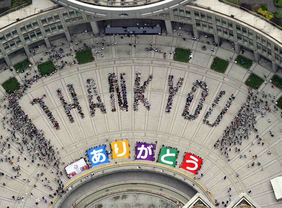 An aerial view shows people sitting in formation to the words "thank you" and displaying signs that collectively read "Arigato" (Thank You) during an event celebrating Tokyo being chosen to host the 2020 Olympic Games, at Tokyo Metropolitan Government Building in Tokyo
